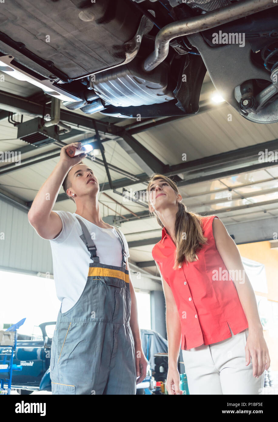 Mécanicien auto fiable contrôler la voiture d'une femme dans un atelier de réparation moderne Banque D'Images