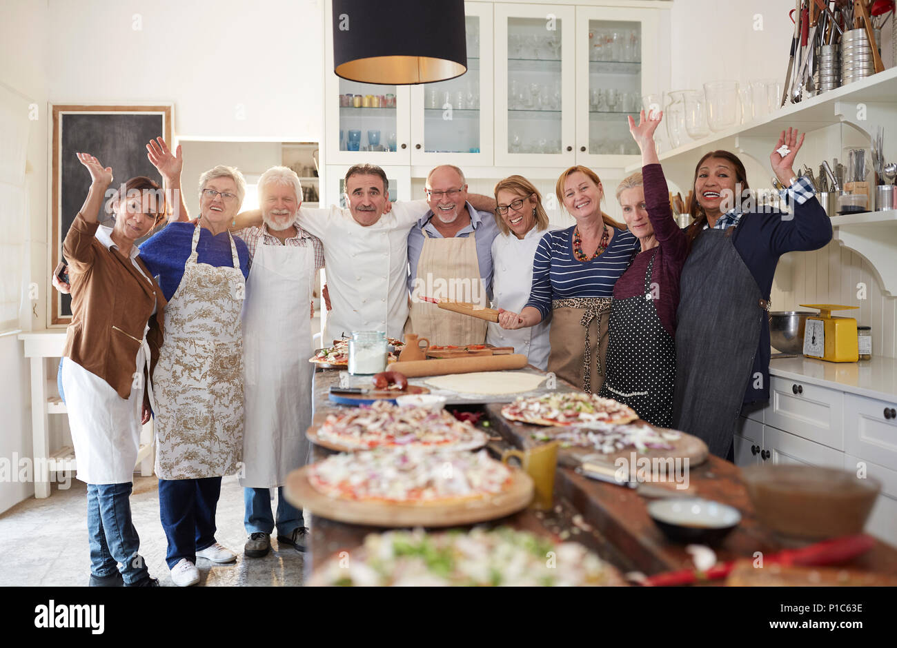 Portrait confiant senior amis et prendre des cours de cuisine chef pizza Banque D'Images