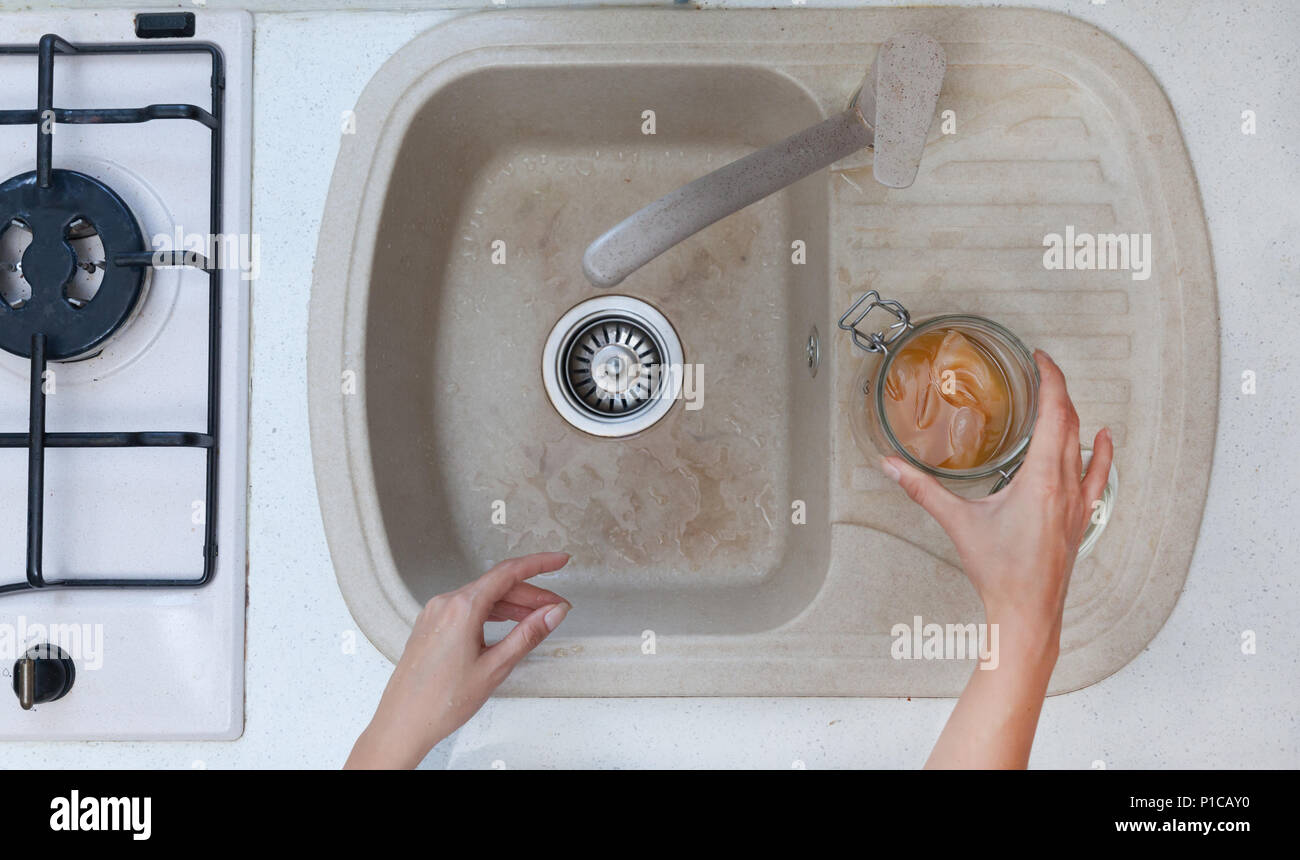 Jeune femme de lui préparer le thé Kombucha dans la cuisine.Elle est le nettoyage du kombucha dans l'eau froide. Banque D'Images