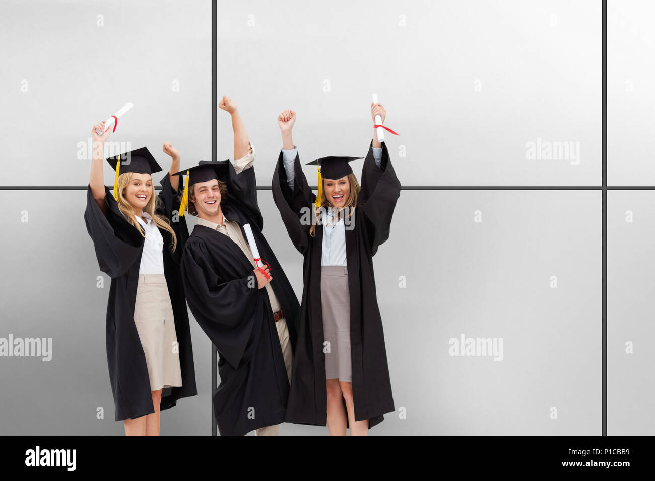 Image composite de trois étudiants diplômés en levant les bras robe Banque D'Images