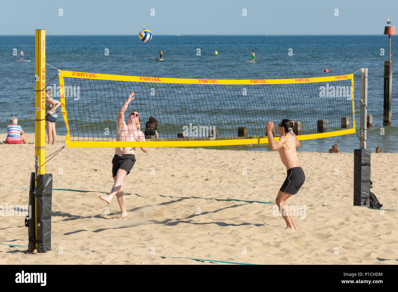 Les jeunes à jouer au volleyball de plage sur la côte sud de l'Angleterre à Boscombe, Bournemouth, Dorset, UK pendant une vague dans un ensoleillement exceptionnel de l'orthographe de l'été. Banque D'Images