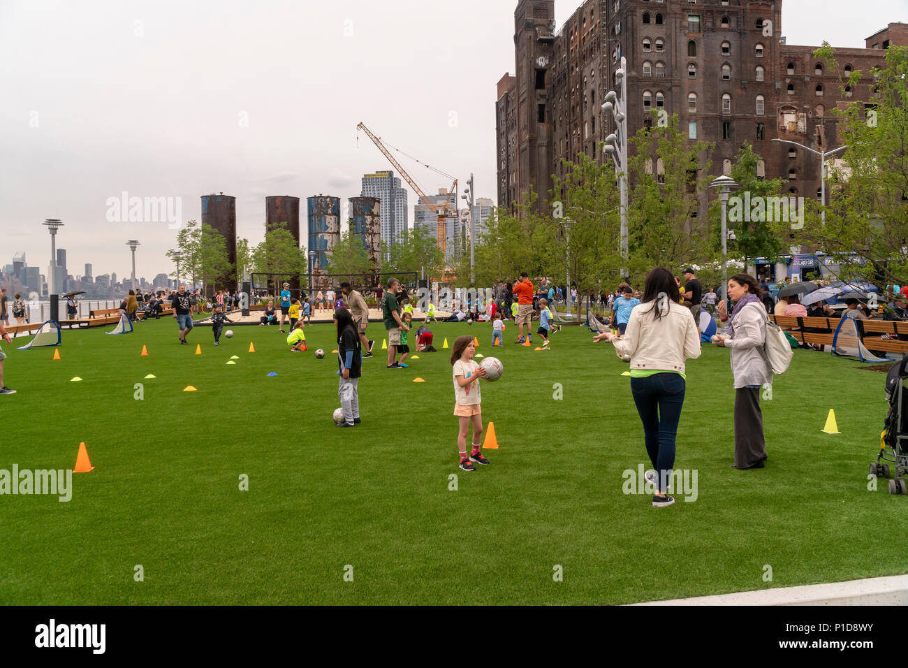 Malgré le mauvais temps des milliers de visiteurs se pressent à l'inauguration du parc de Domino dans le quartier de Williamsburg Brooklyn à New York le dimanche 10 Juin, 2018. L'occupation de l'emplacement de l'Domino Sugar Co., raffinerie fermée en 2004, les cinq acres d'espaces verts a d'eau, des toboggans, une passerelle surélevée, un stand de nourriture et Danny Meyer volley-ball ainsi que de nombreux autres équipements. Conçu par James Corner Field Operations, les architectes de la conception de la ligne haute, la brique de construction de la raffinerie, qui à un moment traitées 50 pour cent de tout le sucre dans le reste des États-Unis pour de Banque D'Images