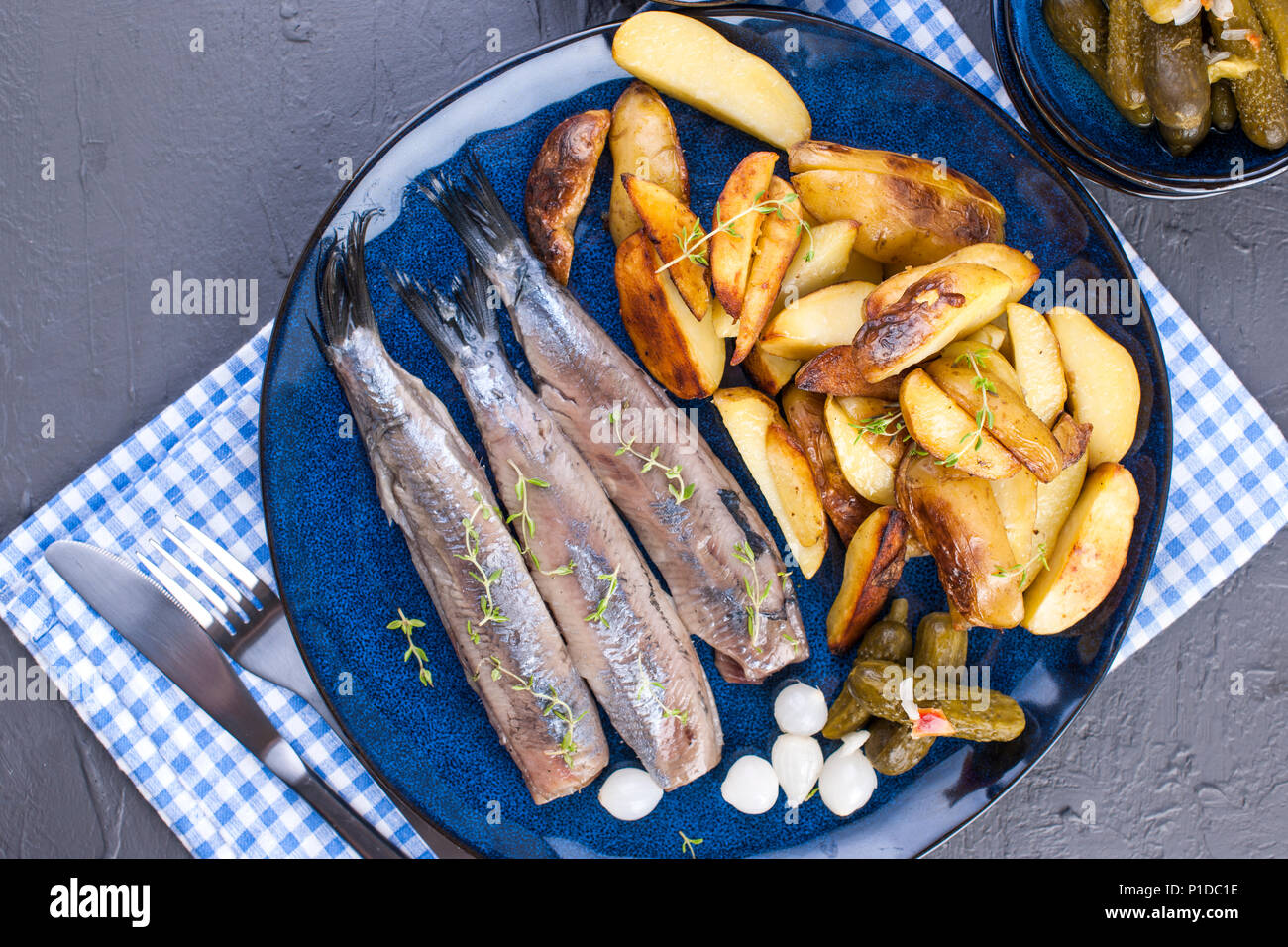 Filets de hareng sur une assiette, cuit au four Pommes de terre et les  concombres et les oignons. De délicieux plats traditionnels de la Hollande.  Délicatesse néerlandais sur une plaque bleue. L'espace