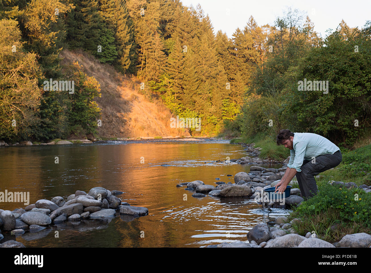 Un homme à la collecte de l'eau d'une rivière de l'Oregon. Banque D'Images