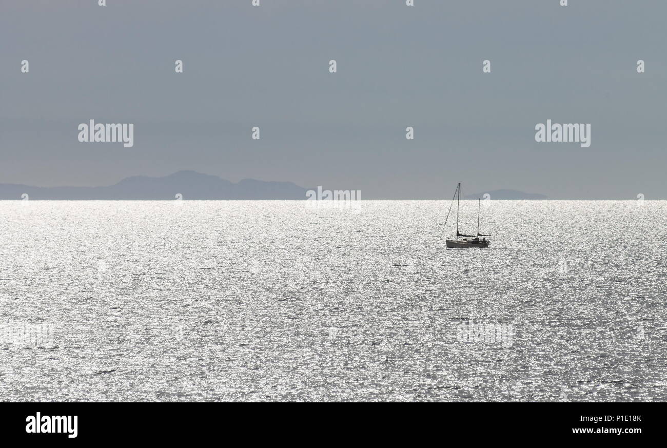 Image paysage d'un yacht sur l'océan de l'eau avec la terre à l'horizon contre un ciel bleu clair avec copie espace Banque D'Images