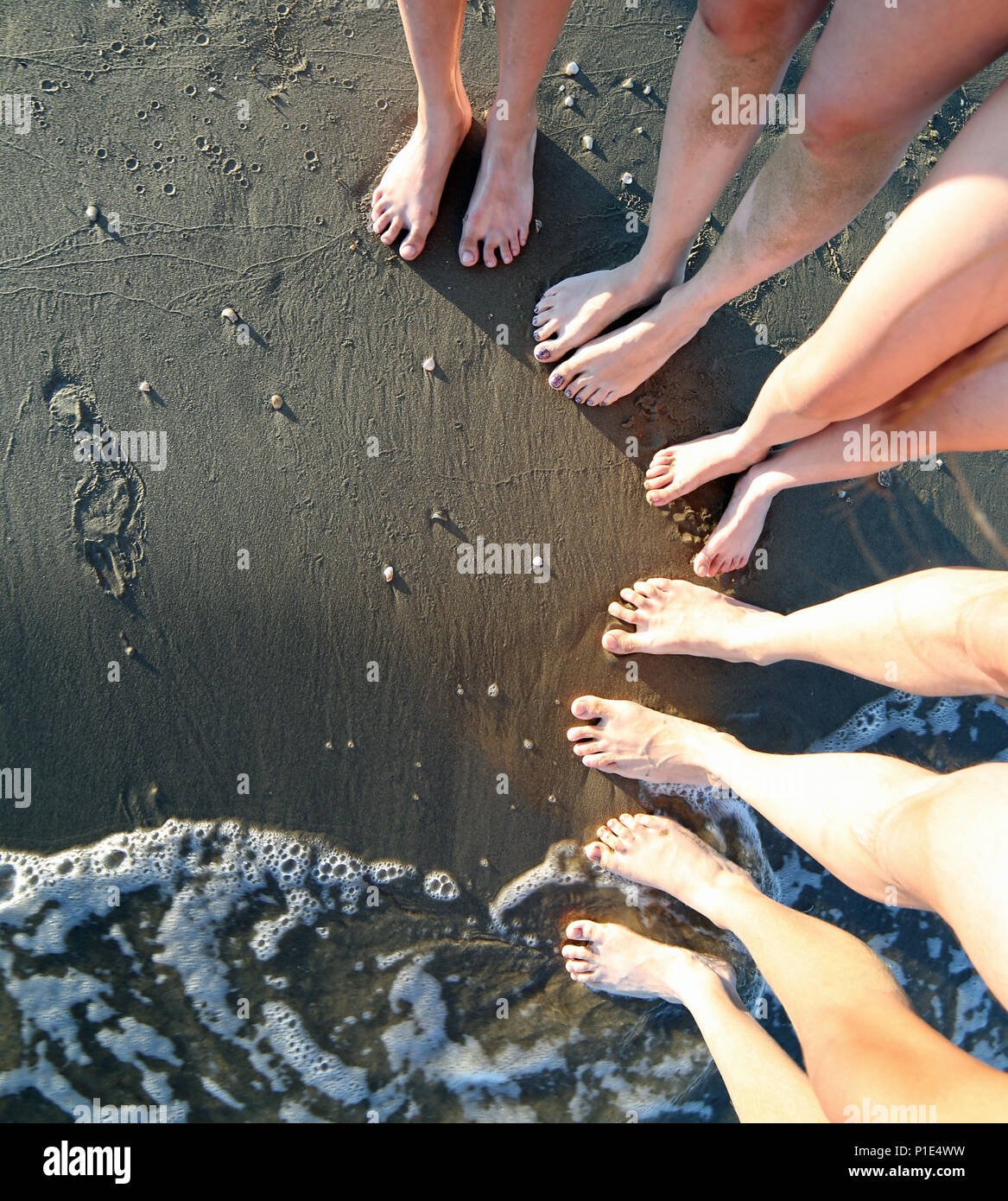 Nu-pieds d'une famille de cinq, avec de longues jambes sur la plage de  sable de la mer en été Photo Stock - Alamy