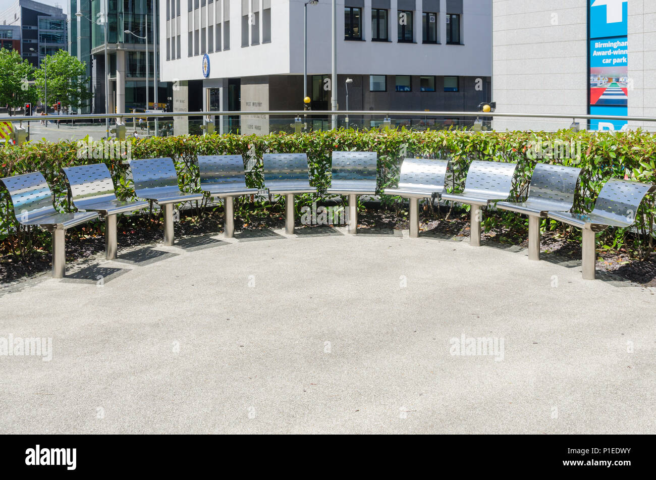 Petit espace extérieur avec demi-cercle de bancs en acier inoxydable Banque D'Images