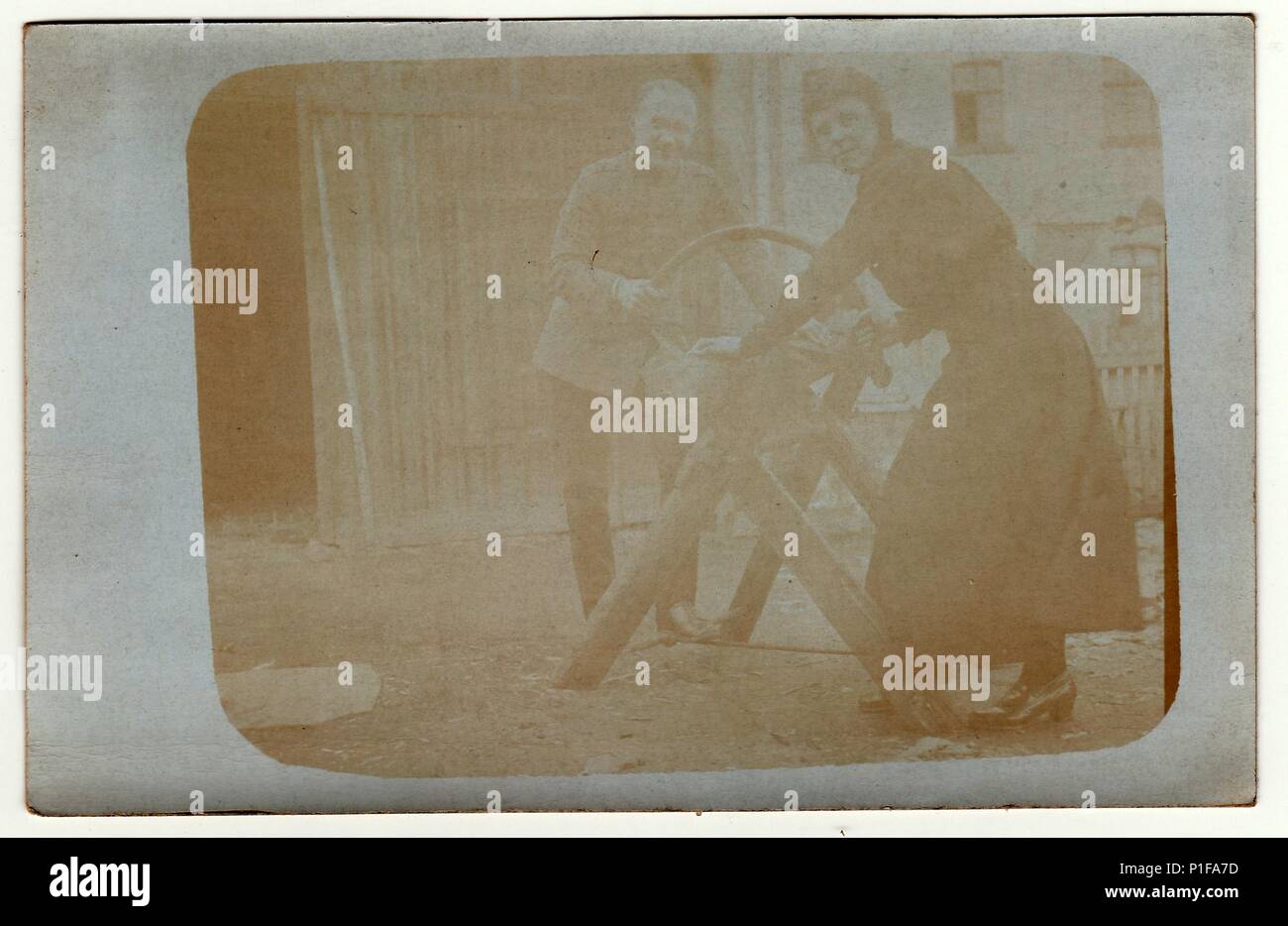 ALLEMAGNE - VERS 1920s: Photo d'époque montre homme et femme coupant un rondins. Ils travaillent dans la cour arrière. Une erreur s'est produite lors du traitement de la photo. Photo antique en noir et blanc. 1920s. Banque D'Images