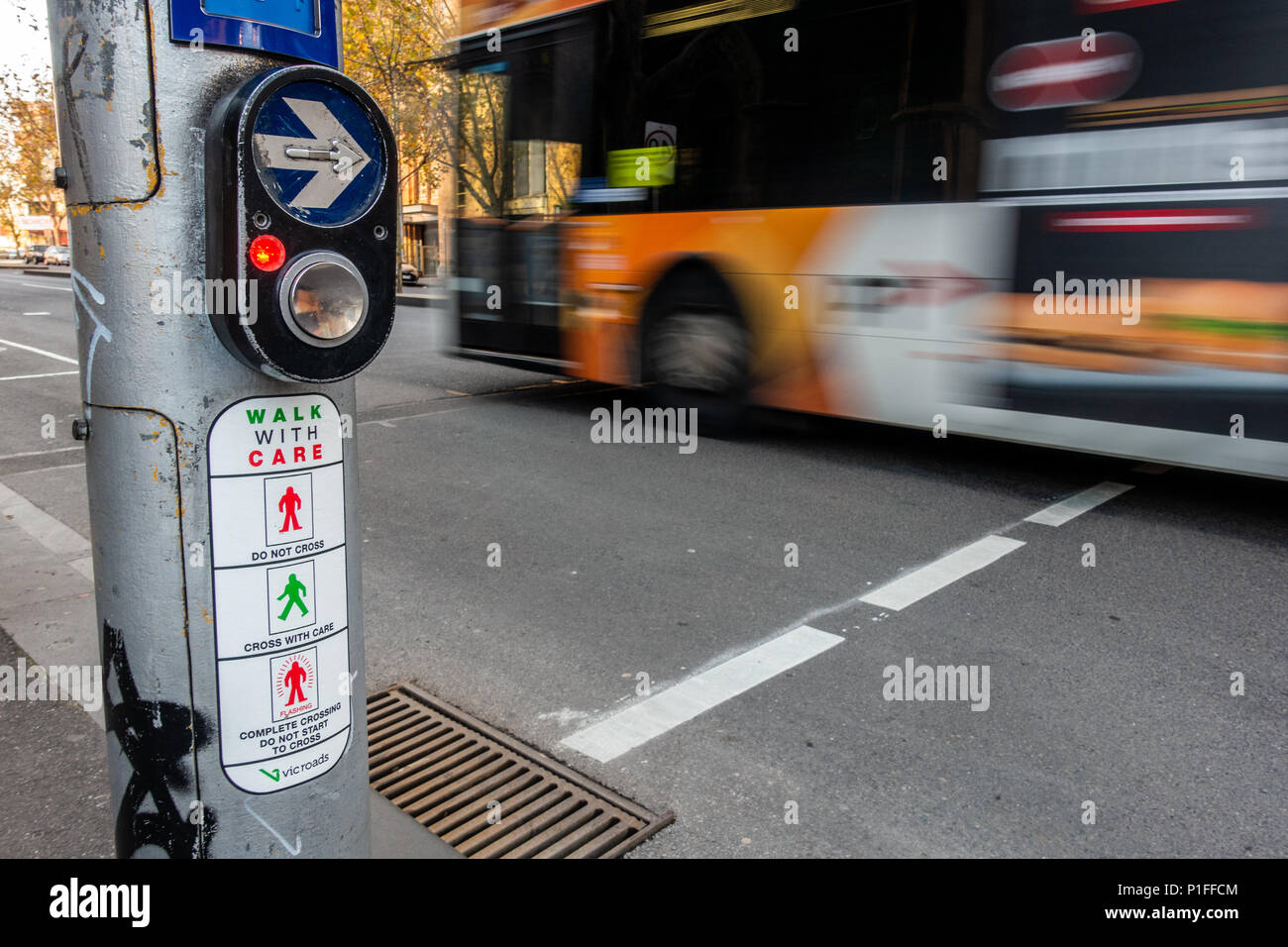 Bouton de passage pour piétons et des instructions à une intersection achalandée avec déplacement de bus sur route comme arrière-plan. Ville de Melbourne, Victoria Australie. Banque D'Images