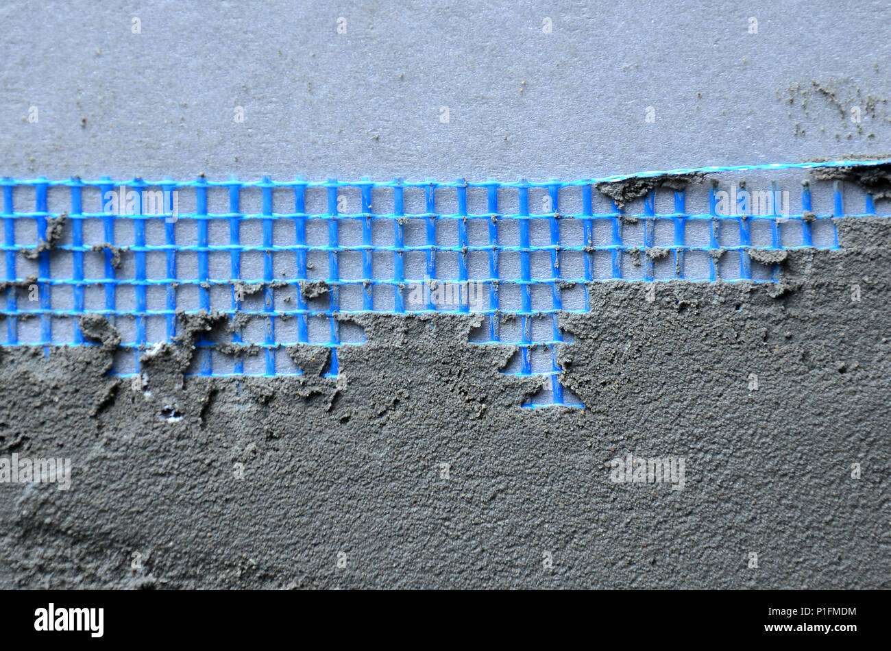 La texture du mur, recouvert de plaques de polystyrène mousse gris, recouvert d'un treillis d'armature bleu et recouvert d'un mélange de collage. Sta Banque D'Images