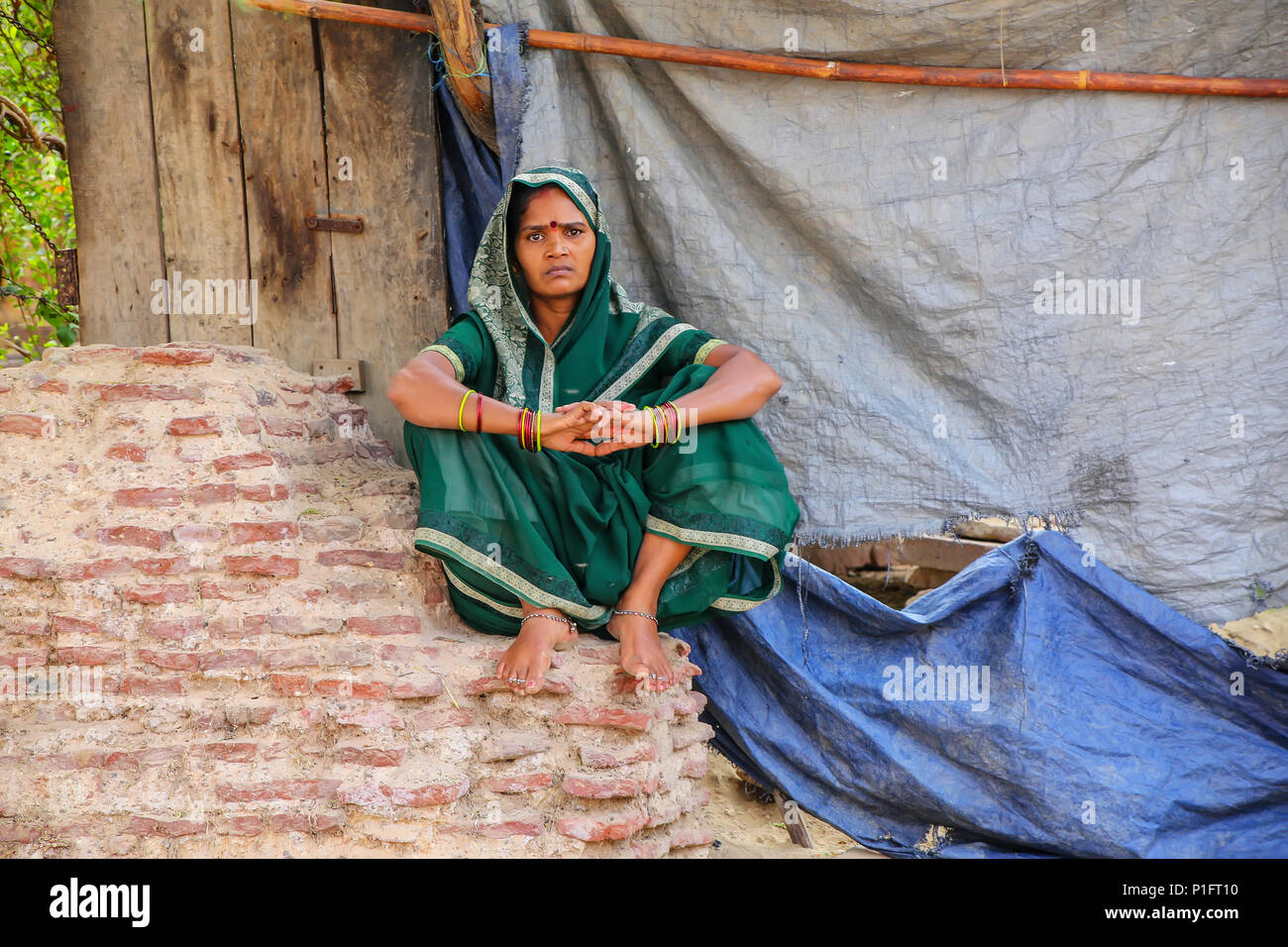 Femme assise sur un mur de brique dans le quartier de Taj Ganj Agra, Uttar Pradesh, Inde. L'Agra est l'une des villes les plus peuplées de l'Uttar Pradesh Banque D'Images