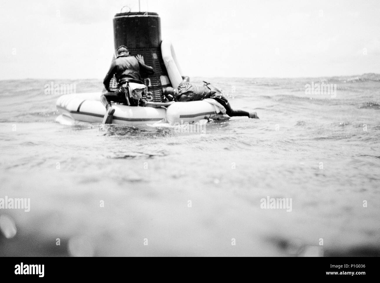 Une équipe de l'US Navy frogman attache un collier à la flottaison Mercury-Atlas 9 (MA-9)foi 7 engin spatial pendant des opérations de valorisation dans le centre du Pacifique près de l'île de Midway. Banque D'Images