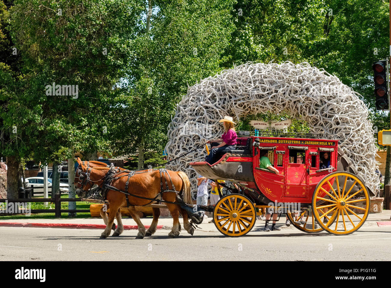 Stagecoach cheval typique du vieux ouest américain transporte les touristes dans la région de Jackson Wyoming en face de l'entrée du parc emblématique arc de bois. Banque D'Images