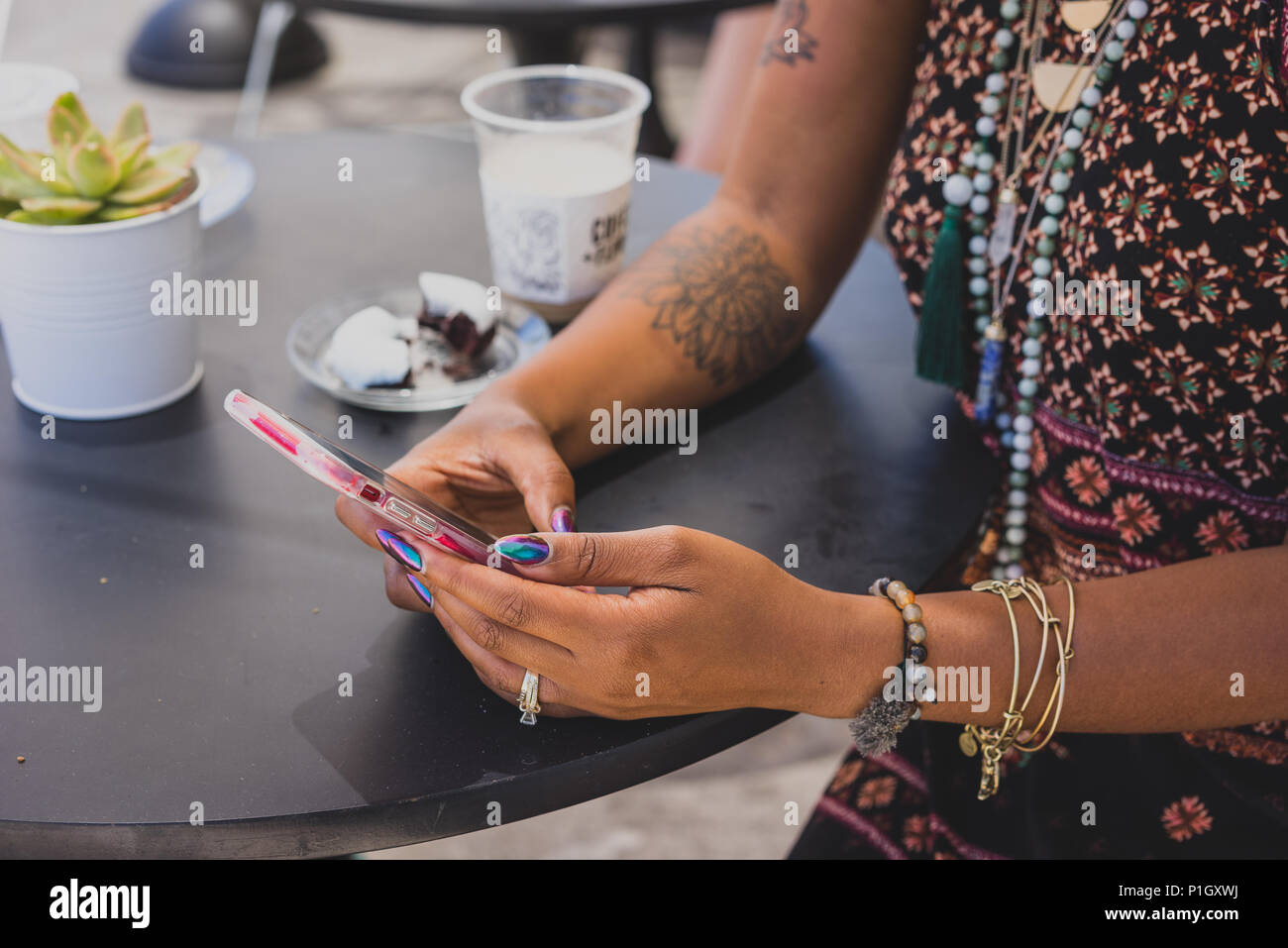 Gros plan du black woman's hands using cell phone at coffee shop Banque D'Images