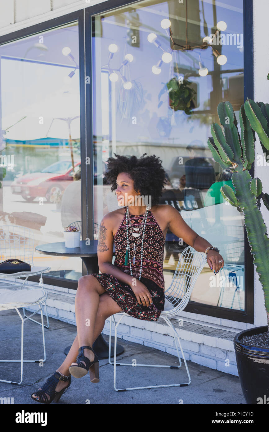 Femme noir assis à une table à l'extérieur d'un cafe Banque D'Images
