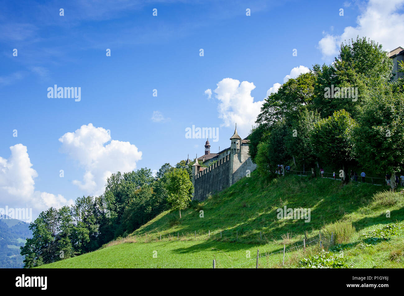 Vue de remparts et porte de Gruyeres, vieille ville Suisse. Paysage verdoyant, surmonté d'arbres et colline blue cloudy sky Banque D'Images