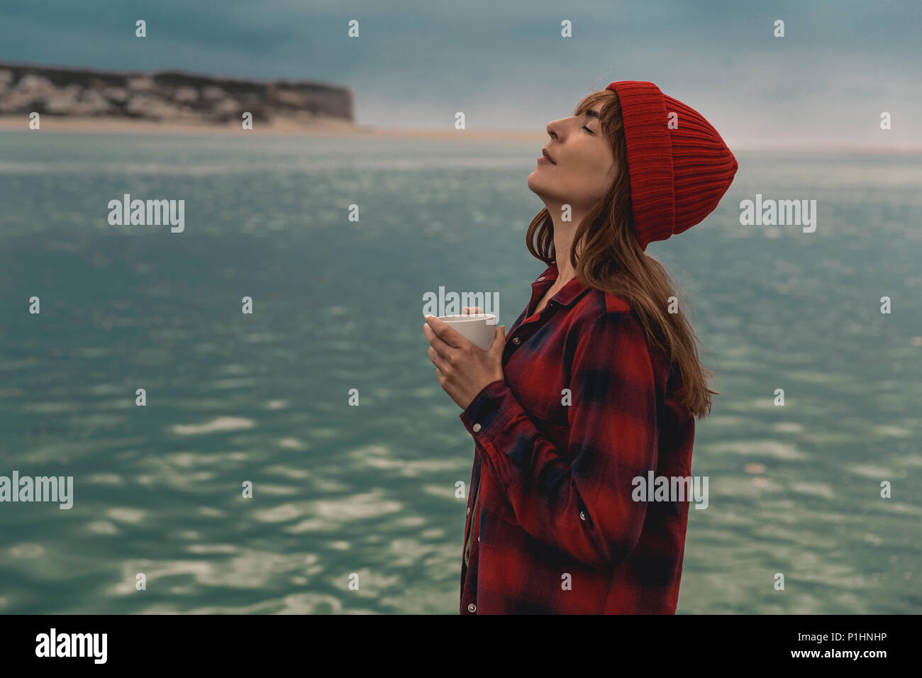 Belle femme profitant de son jour dans le lac avec une tasse de café chaud Banque D'Images