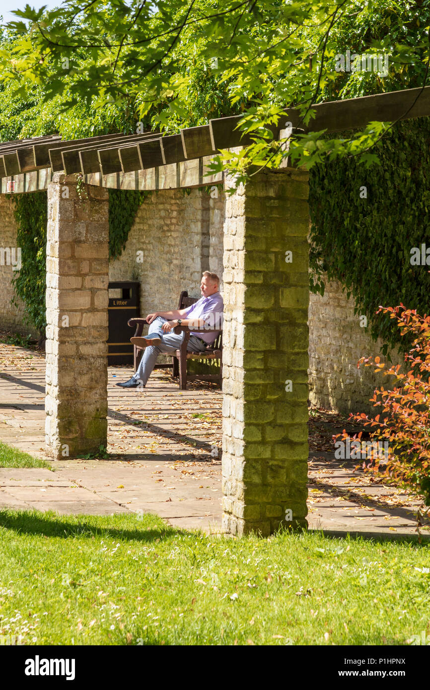 Jardins de l'abbaye de Malmesbury, un visiteur se trouve dans le soleil et des silences, Wiltshire, UK Banque D'Images