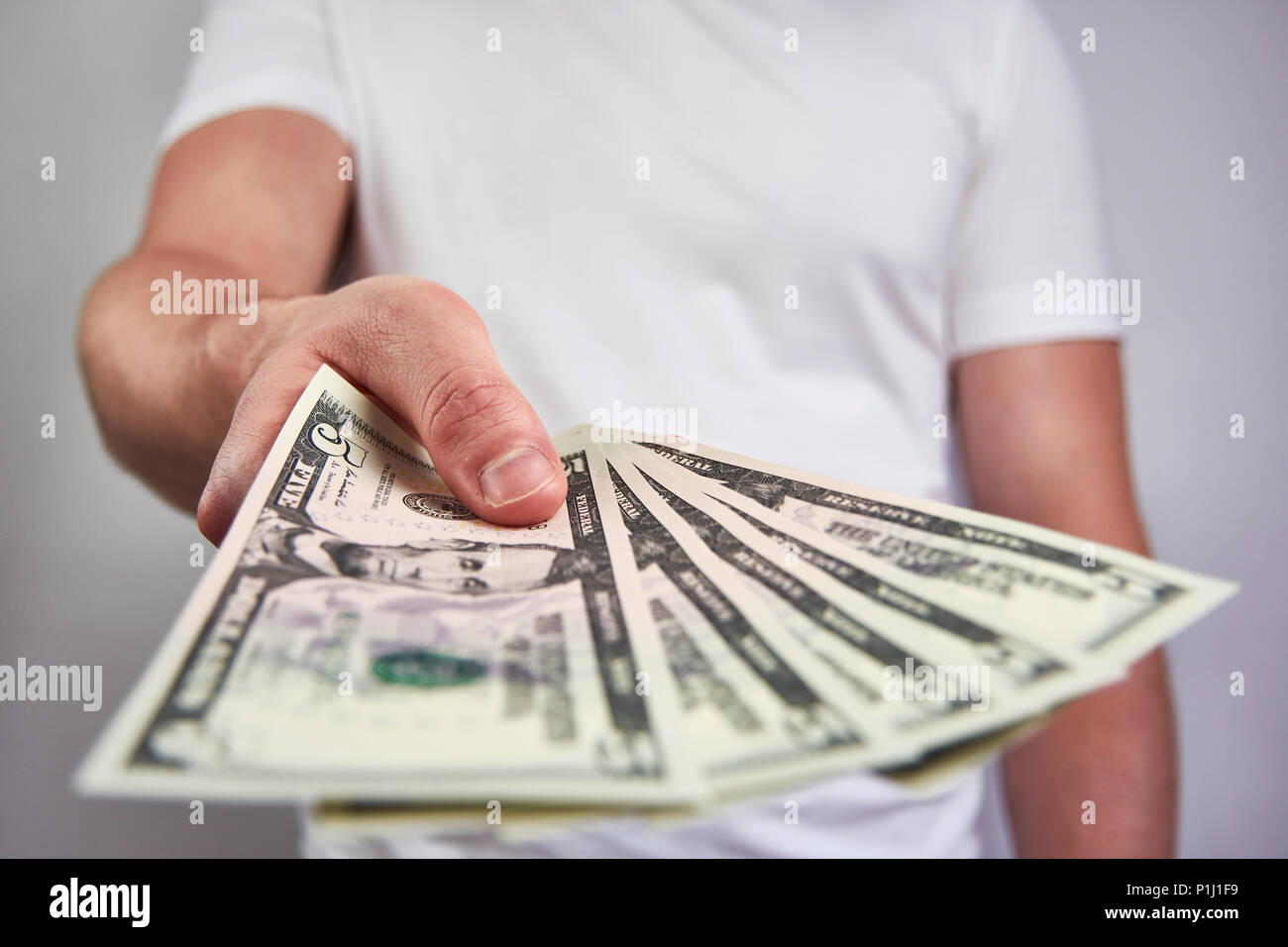 Un jeune homme tenant un billet de cinq dollars, ce qui en fait - sur un fond blanc Banque D'Images