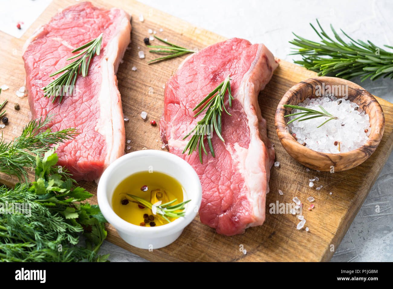 Faux filet de boeuf cru steak avec des herbes et des ingrédients. La viande fraîche prête à la cuisson. Banque D'Images