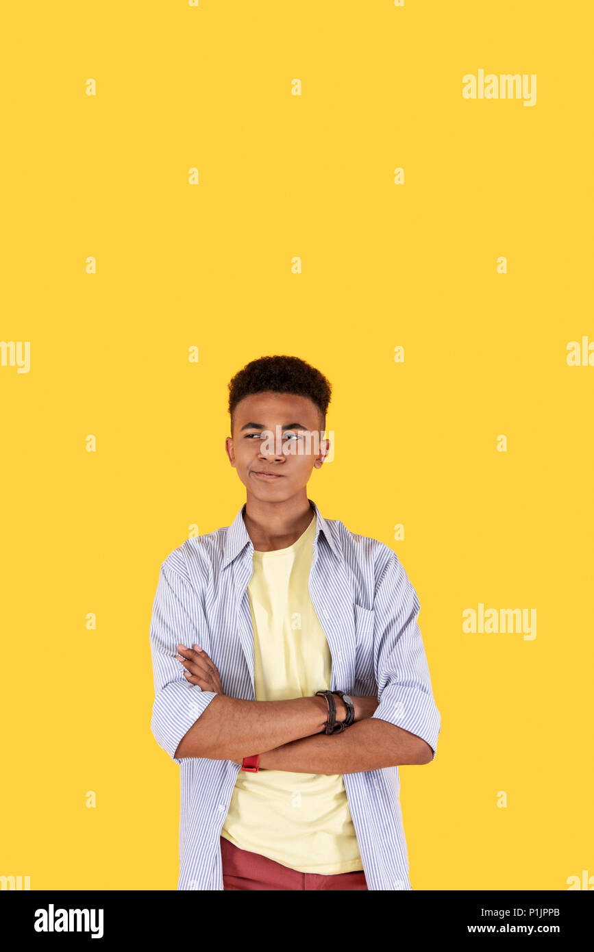Réfléchis agréable homme debout contre fond jaune Banque D'Images