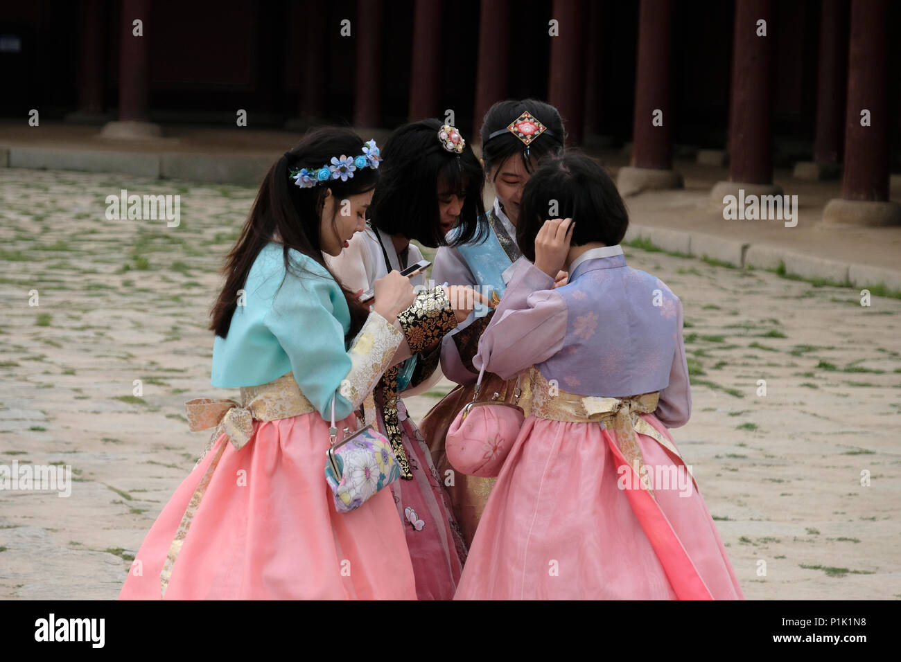 Les jeunes femmes coréennes en costumes traditionnels en utilisant leur téléphone cellulaire à Gyeongbokgung ou le Palais de Gyeongbok qui était le principal palais royal de la dynastie Joseon. Construit en 1395 dans la ville de Séoul, capitale de la Corée du Sud Banque D'Images