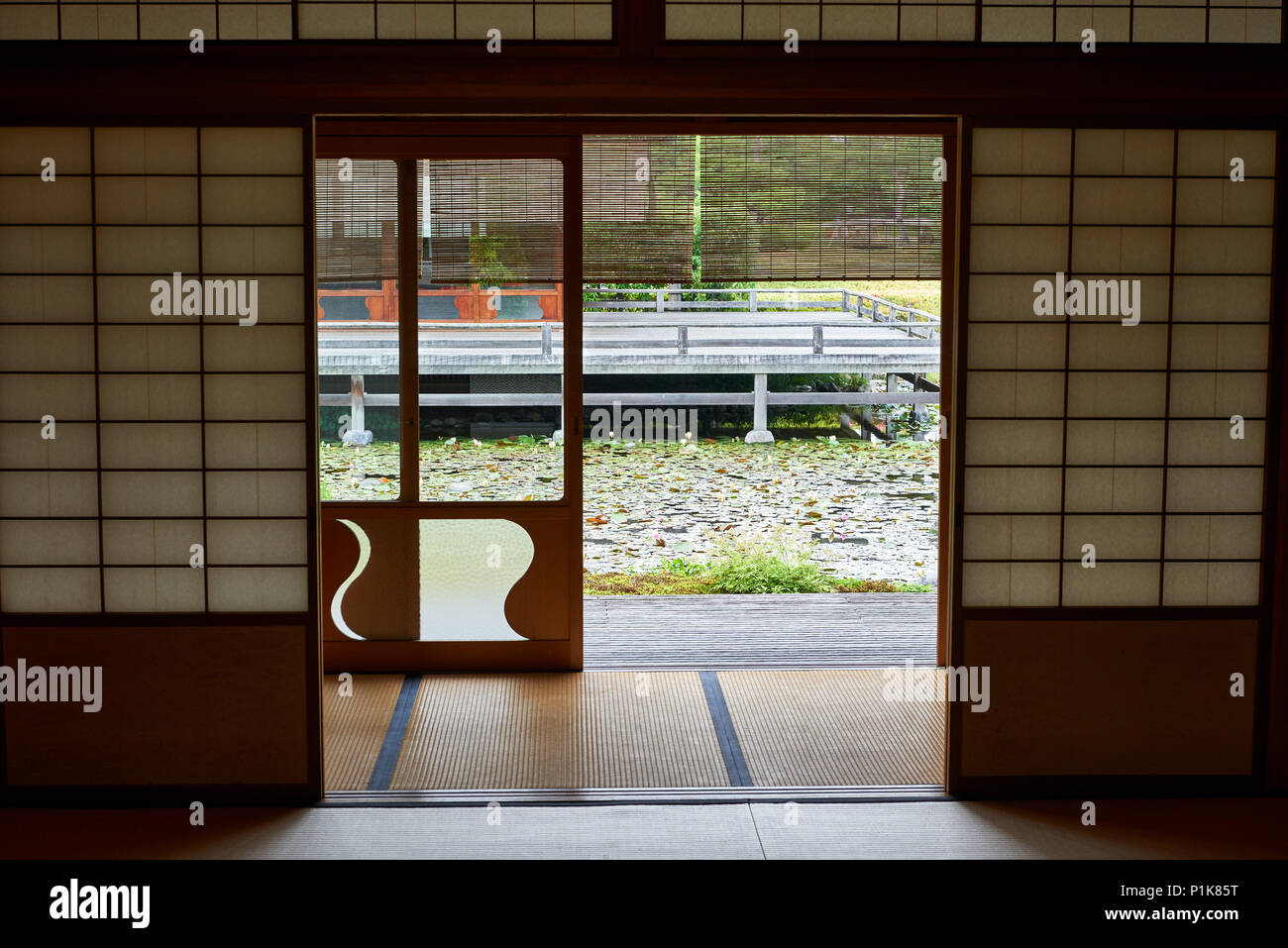 Vue sur un étang et un salon de thé traditionnel japonais par shoji porte. Banque D'Images
