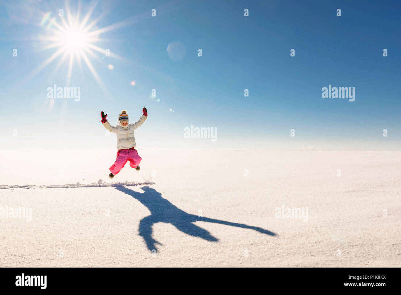 Girl jumping mid air dans un paysage rural enneigé Banque D'Images