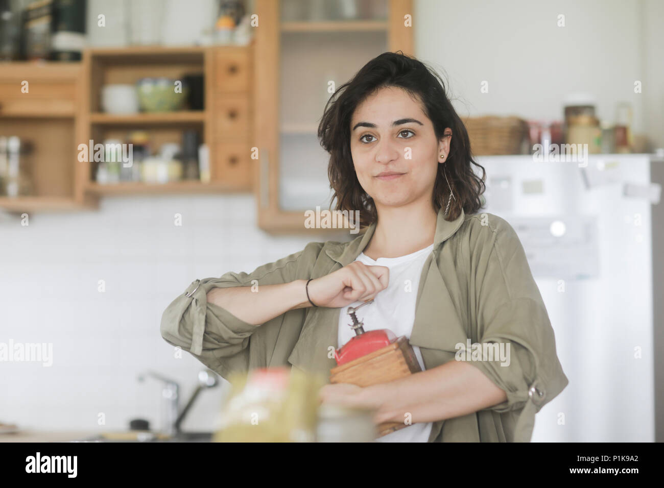 Femme debout dans la cuisine à l'aide d'un vieux moulin à café Banque D'Images