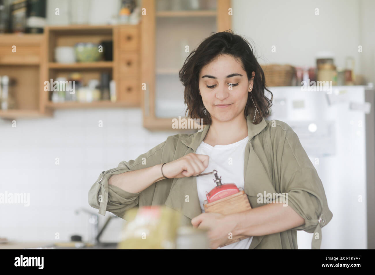 Femme debout dans la cuisine à l'aide d'un vieux moulin à café Banque D'Images