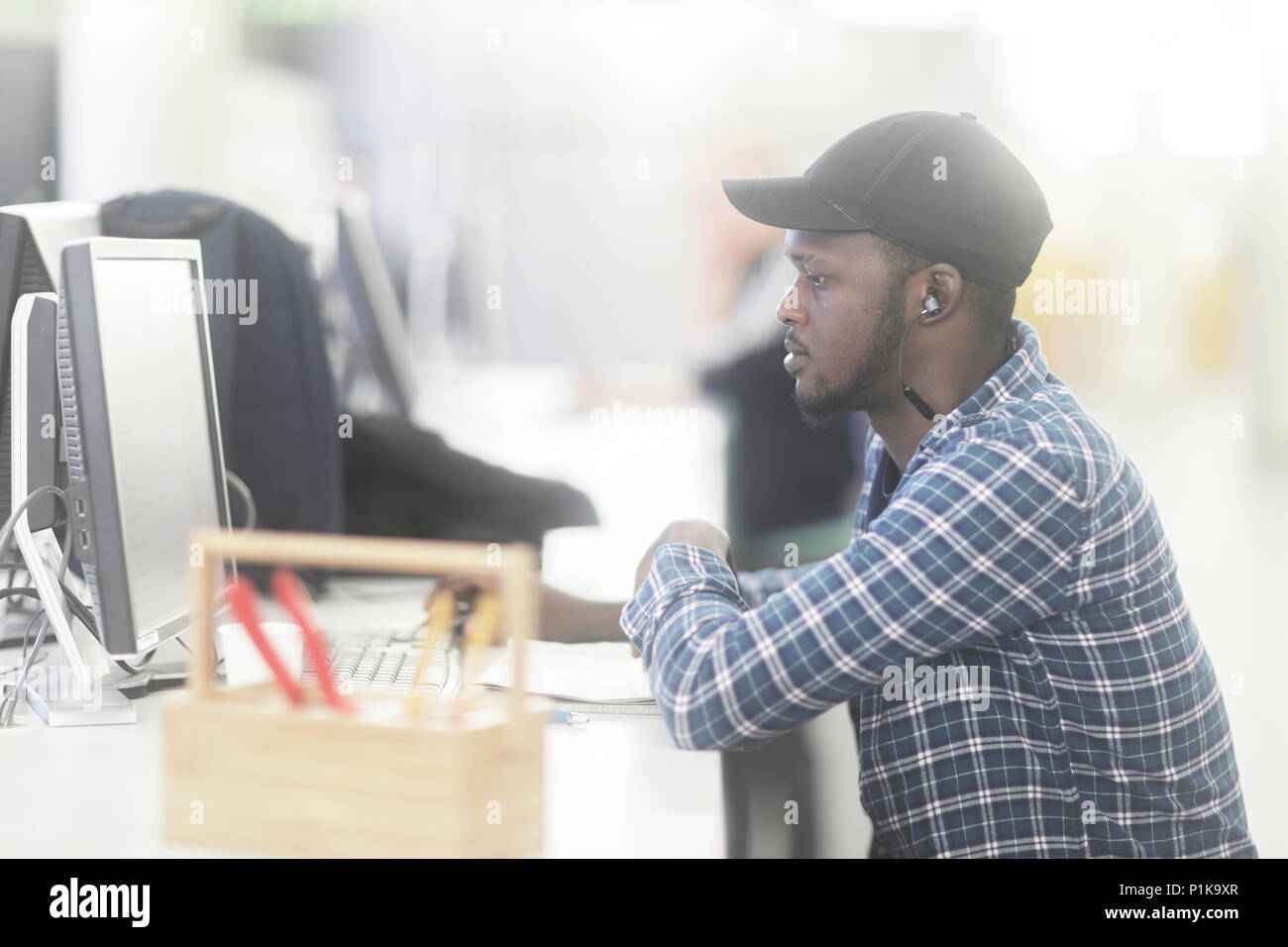 L'homme assis à un bureau à l'aide d'un ordinateur avec des outils sur son bureau Banque D'Images