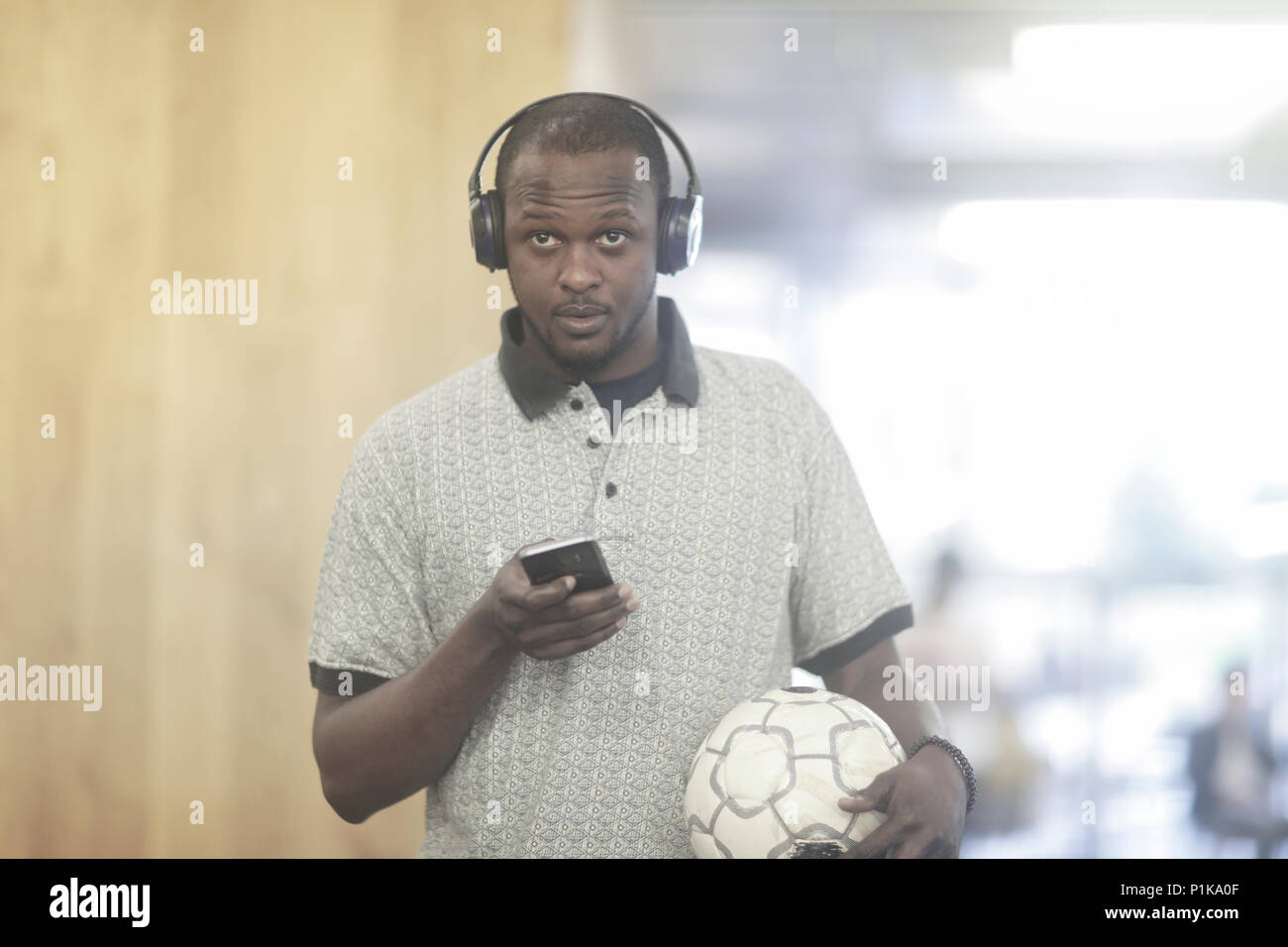 Homme portant un casque tenant un téléphone portable et d'un foot Banque D'Images