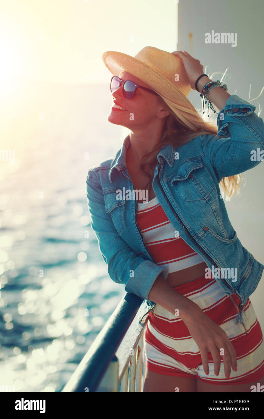 Young blonde woman traveler posant sur le pont transbordeur dans le coucher du soleil Banque D'Images