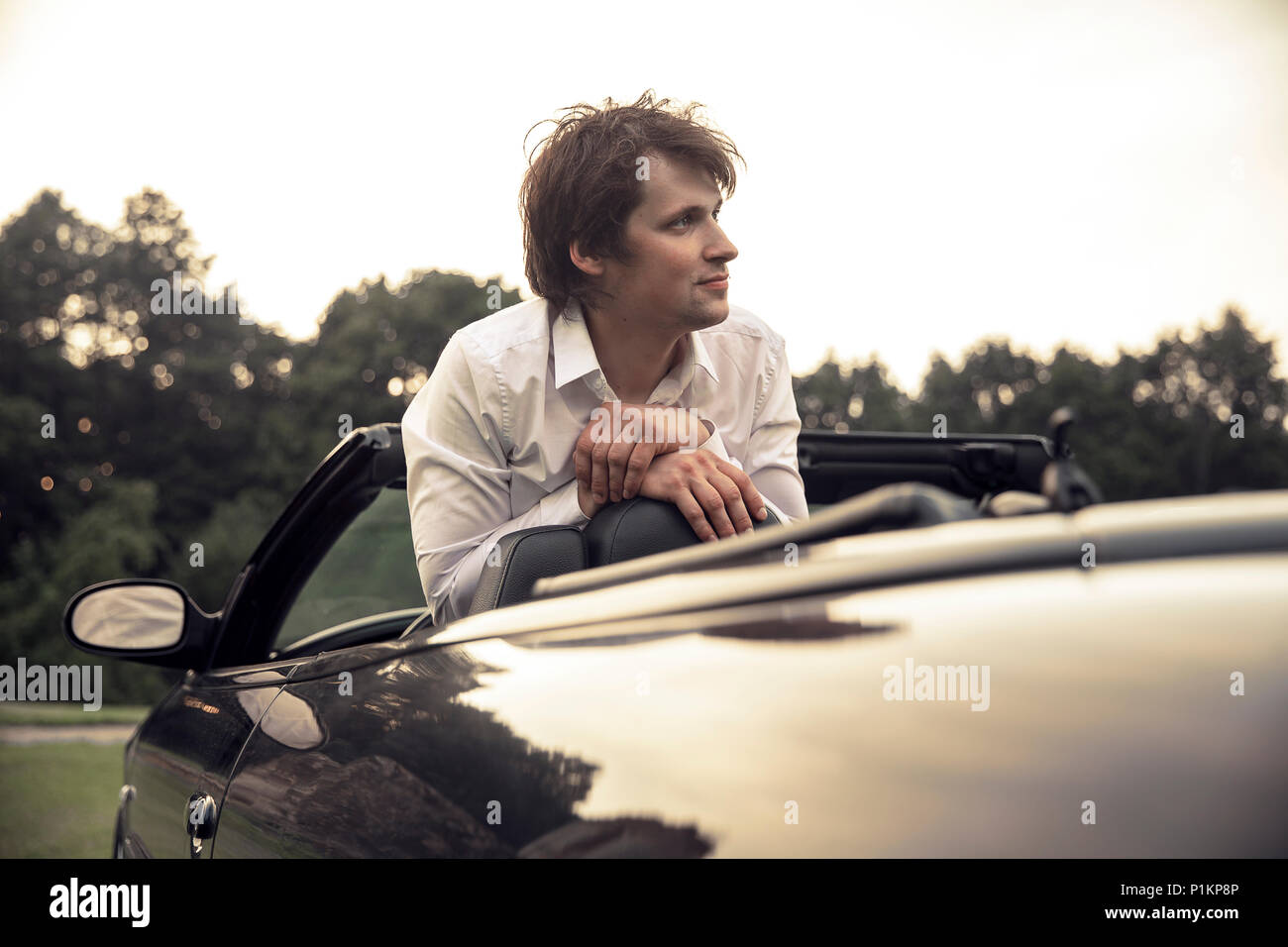 Beau jeune homme assis dans une voiture. Voyages et aventures concept. Tonique photo Banque D'Images
