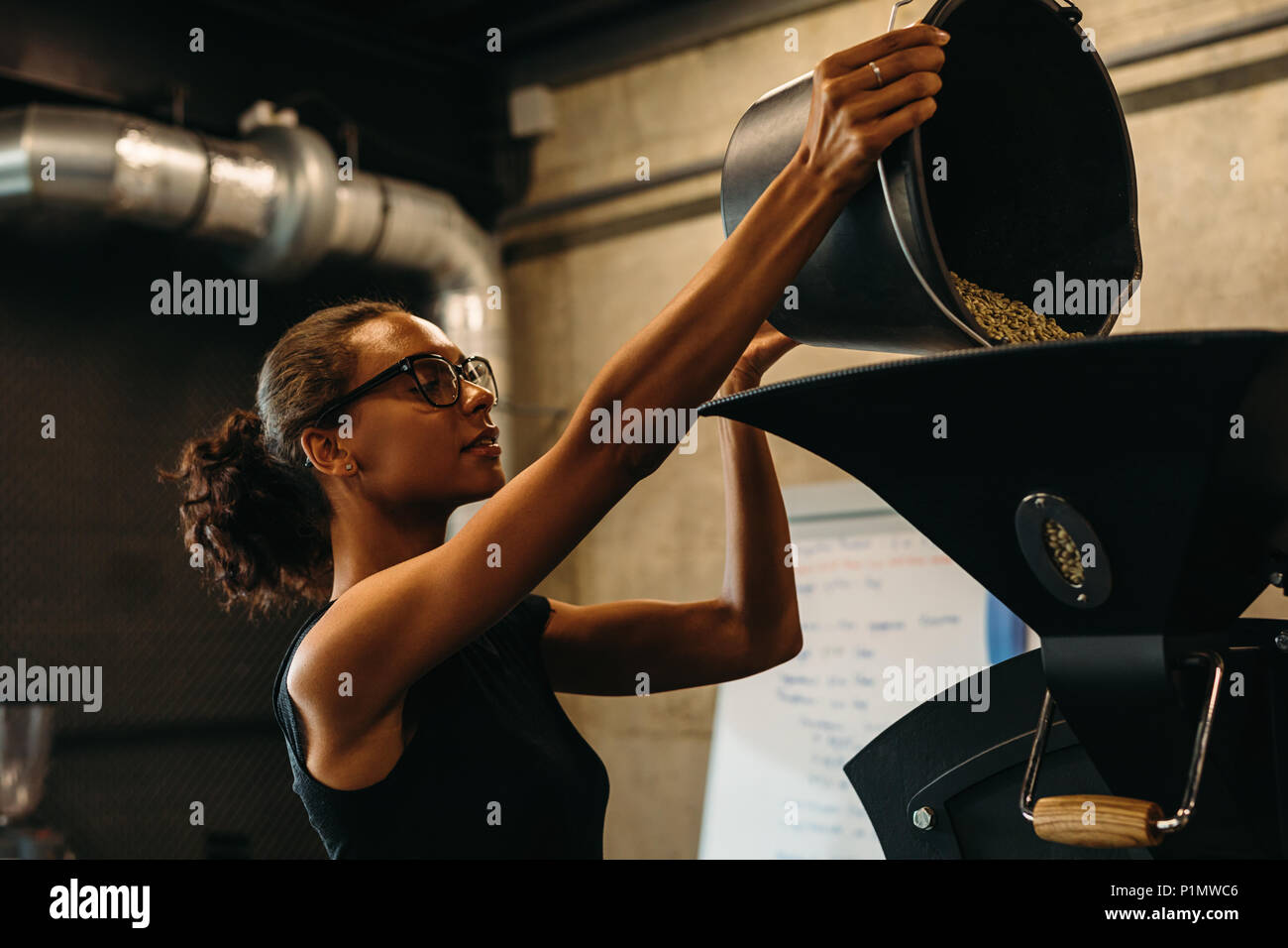 Woman putting grains de café dans la machine de torréfaction de café Banque D'Images