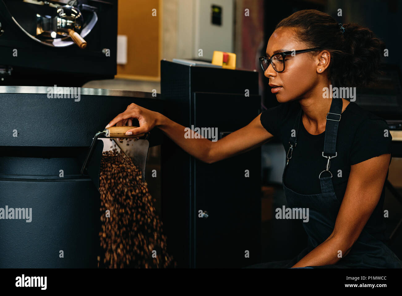 Jeune entrepreneur travaillant dans la production de café. Café en grains torréfaction à la sortie d'un linge. Banque D'Images