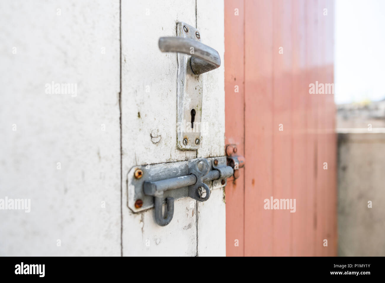 Poignée de porte et boulon de verrouillage sur un vieux hangar blanc et  rose Photo Stock - Alamy