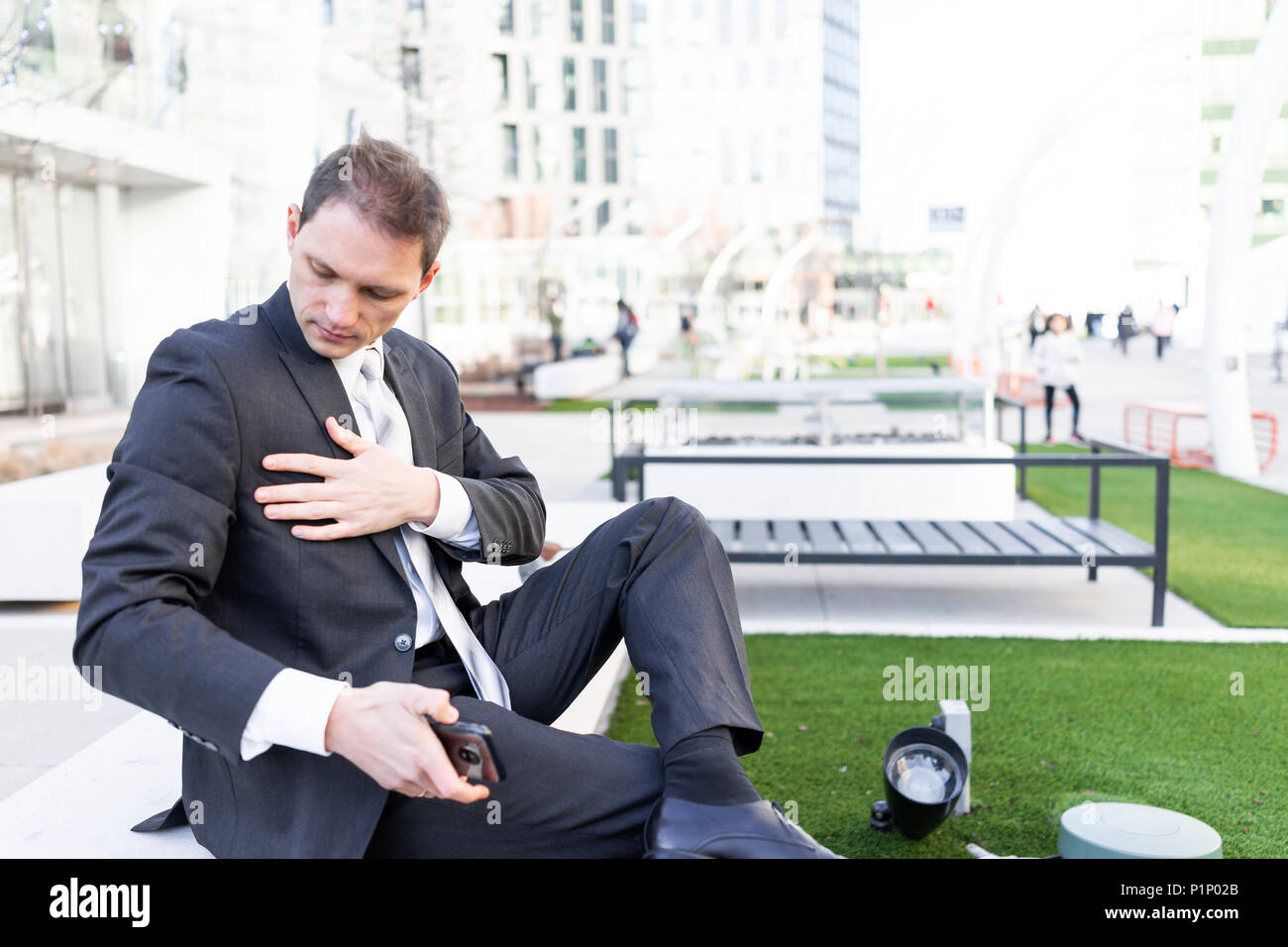 Jeune homme d'époussetage nettoyage off suit sitting on bench in urban  green Park à la recherche vers le bas avec cravate sur pause interview  Photo Stock - Alamy