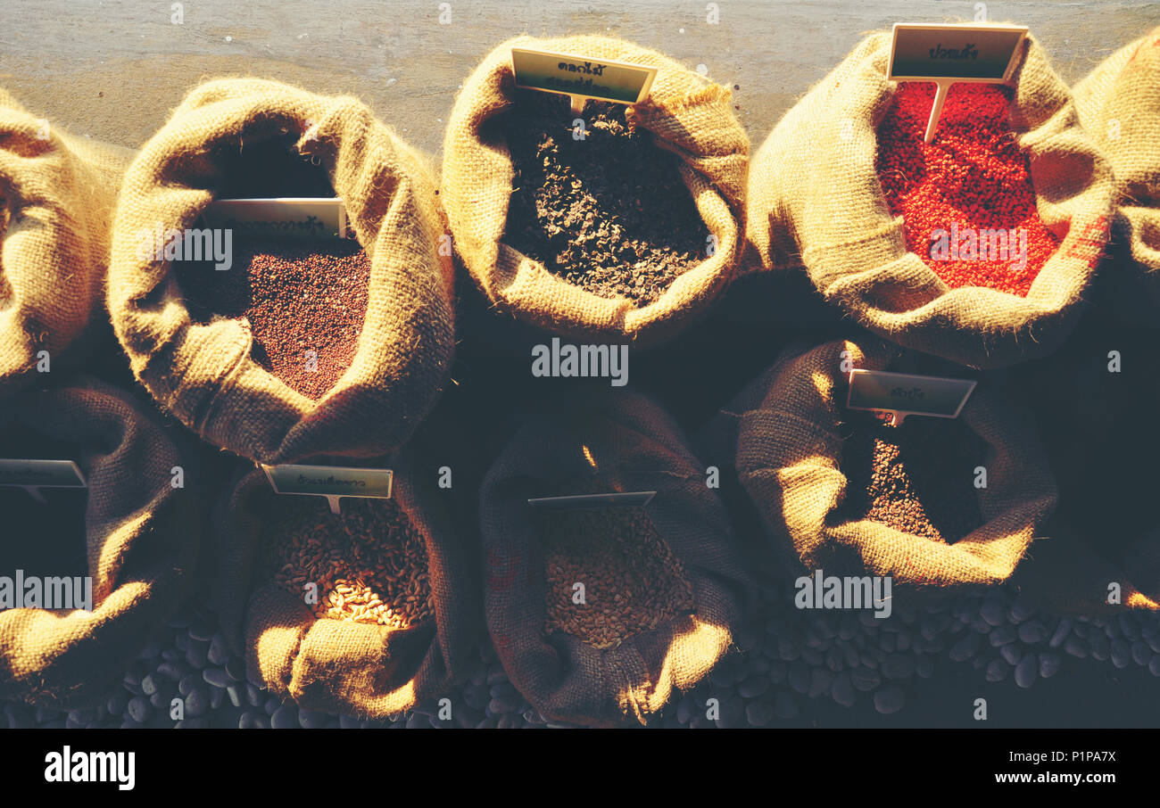 Graines de moutarde, de lin, de tournesol et de coriandre sont déversées à partir de sacs de linge Banque D'Images