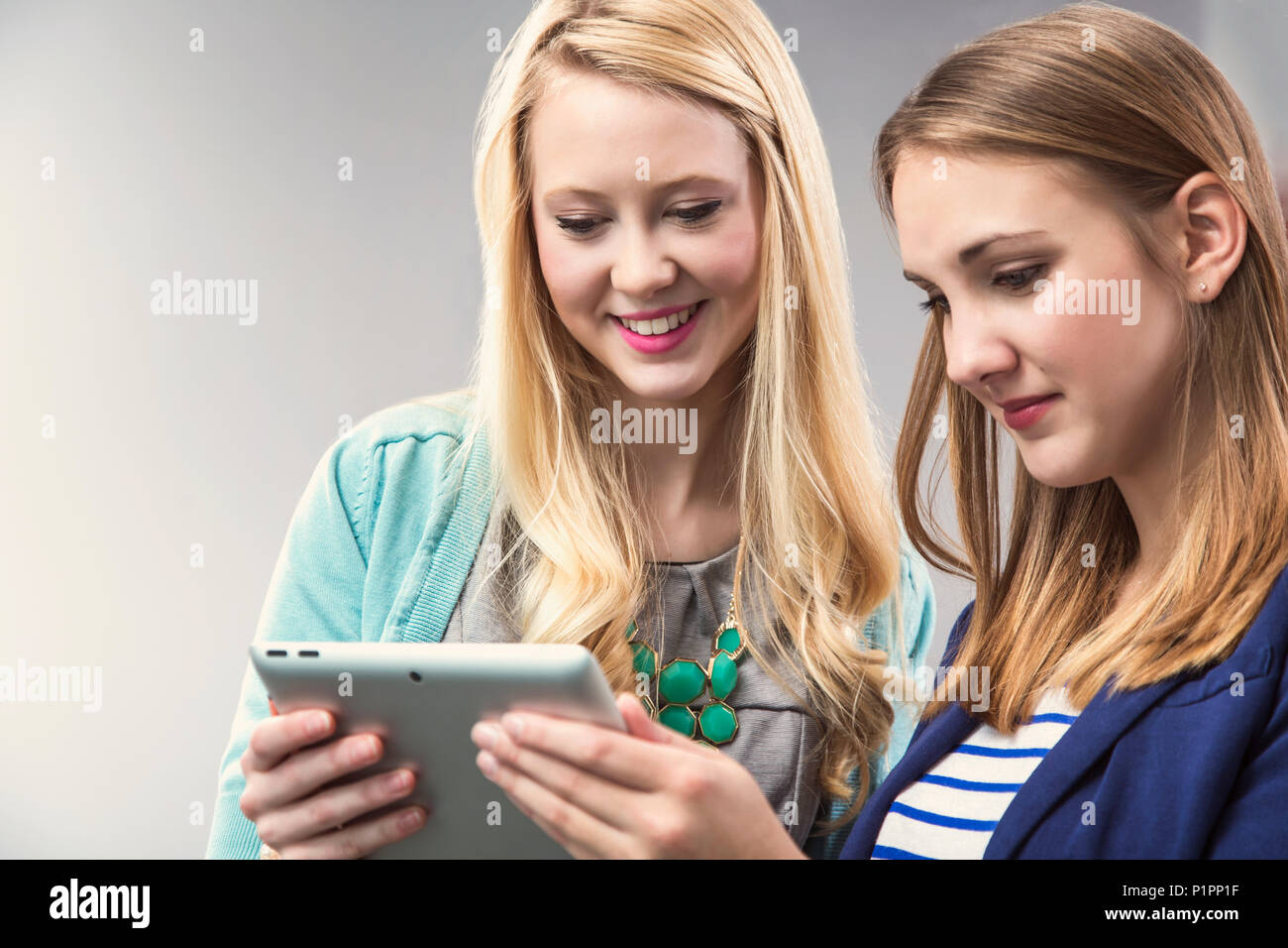 Deux belles jeunes femmes qui sont des professionnels qui travaillent ensemble d'affaires du millénaire et à la recherche à un comprimé à leur lieu de travail Banque D'Images