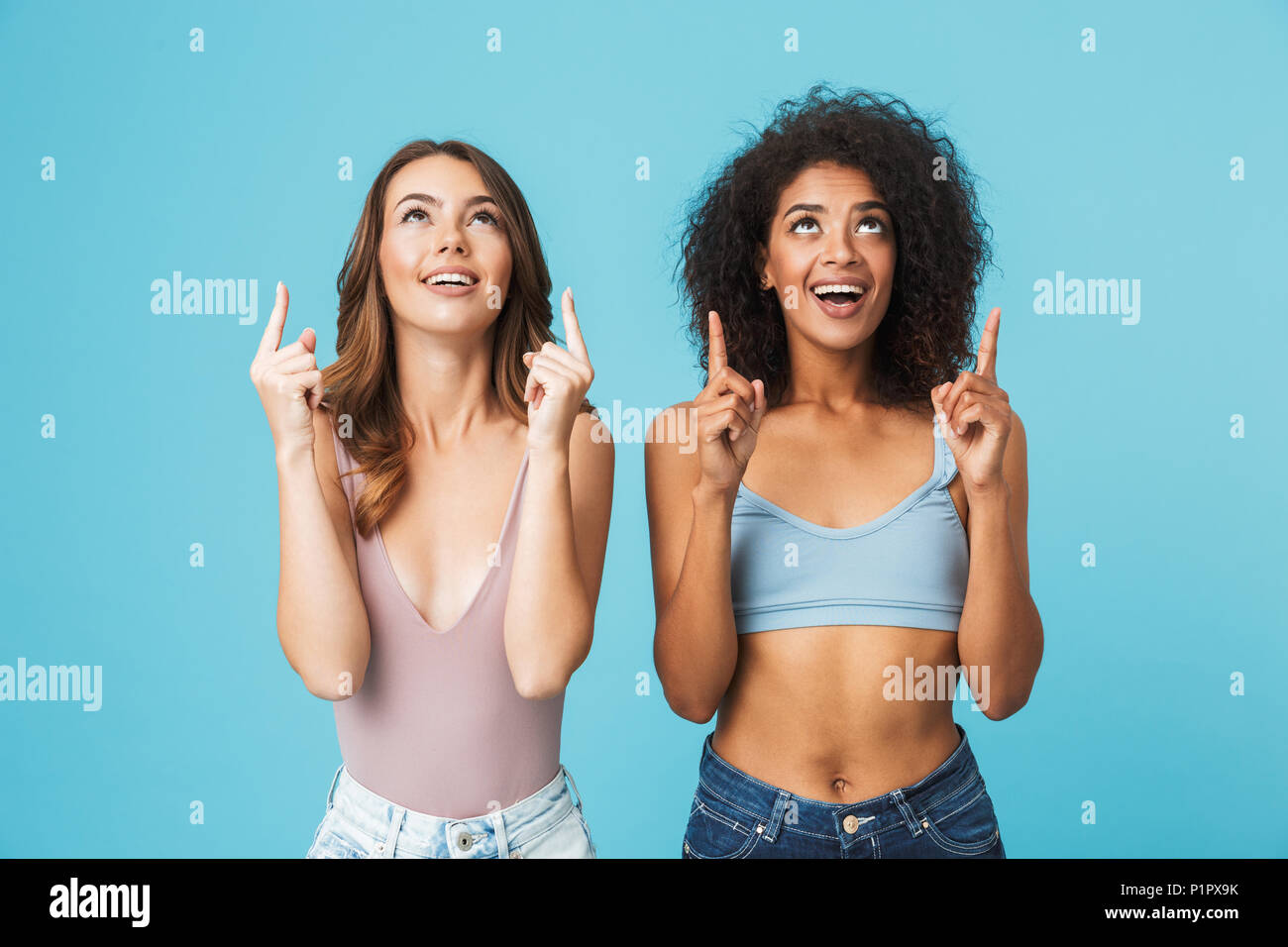 Deux professionnels des jeunes filles habillés en vêtements d'été à pointage copie espace isolé sur fond bleu Banque D'Images