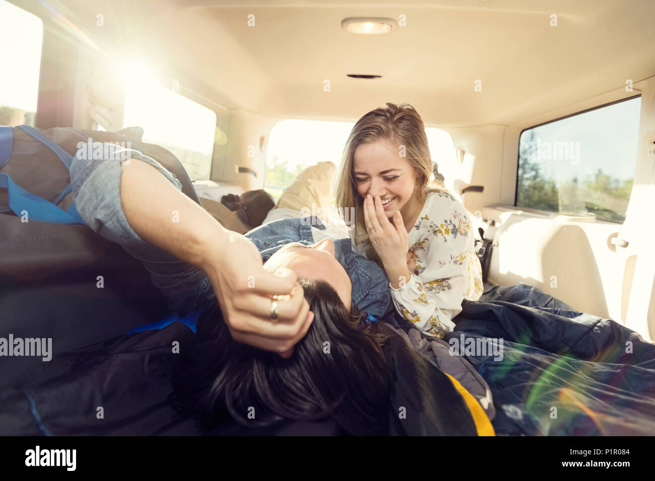 Un jeune couple se trouve dans l'arrière de leur véhicule lors d'un voyage en voiture parler et rire ensemble ; Edmonton, Alberta, Canada Banque D'Images