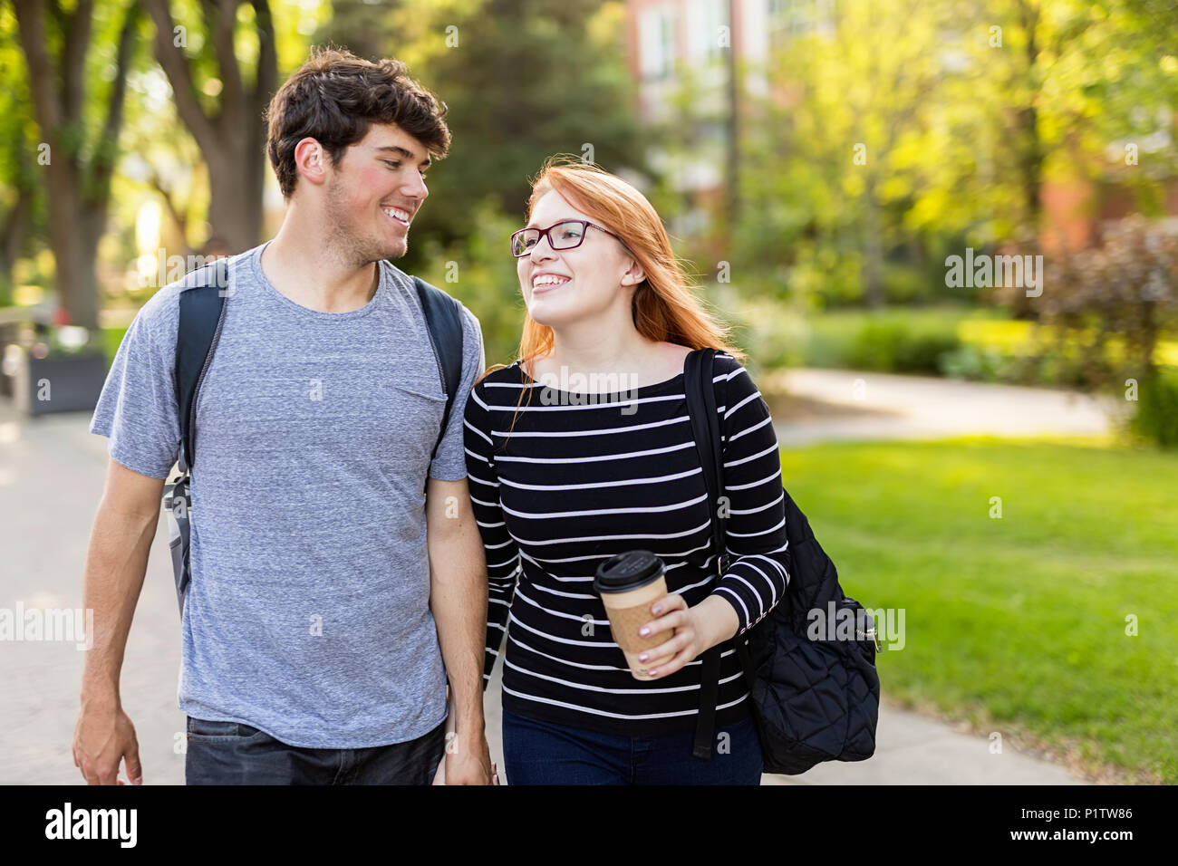 Un jeune couple en train de marcher et tenir la main tout en marchant à travers un campus universitaire ; Edmonton, Alberta, Canada Banque D'Images