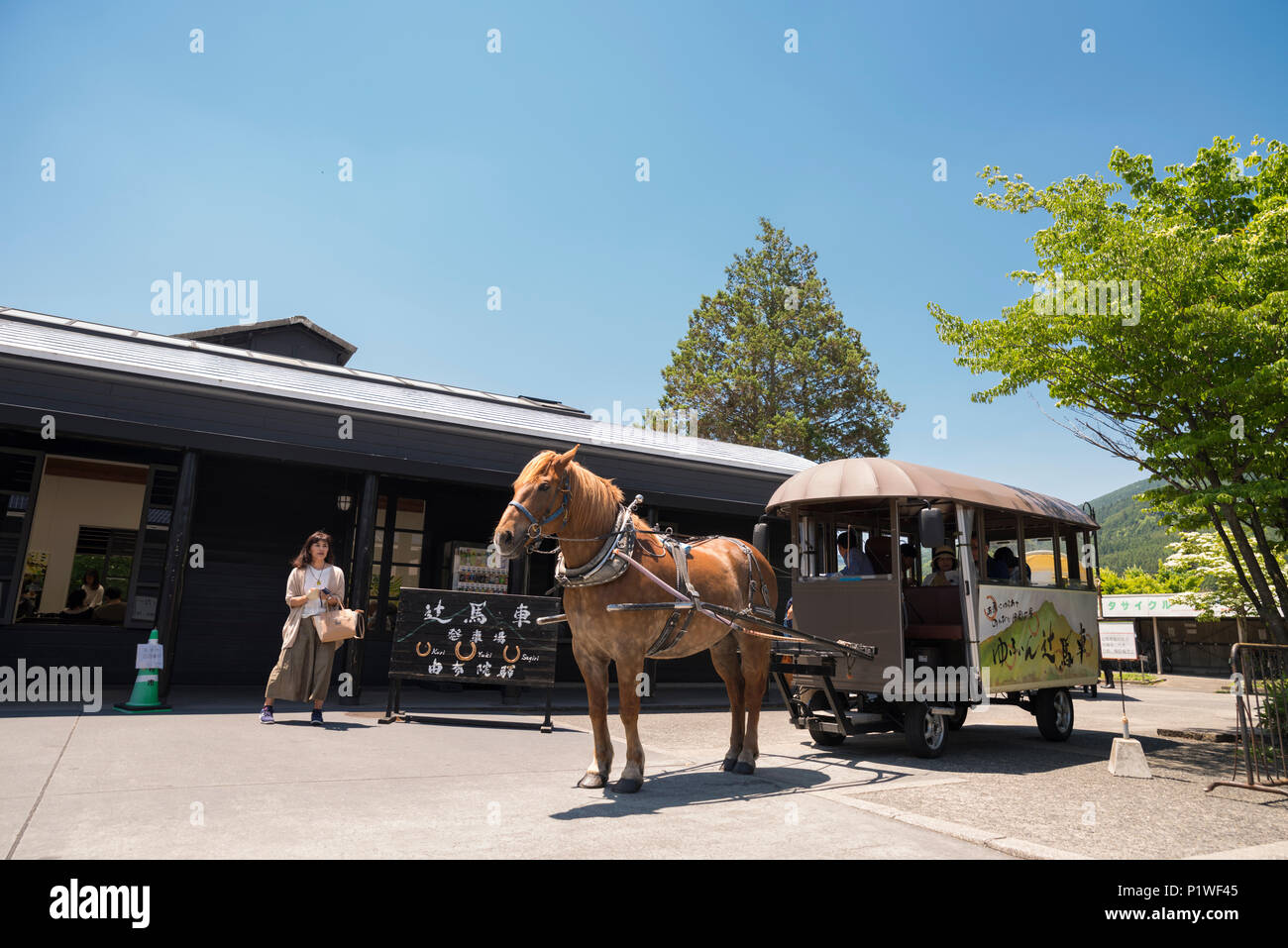 En chariot à cheval de touristes à l'extérieur de la gare à Yufuin Onsen Resort, Oita, Kyushu, Japon Banque D'Images