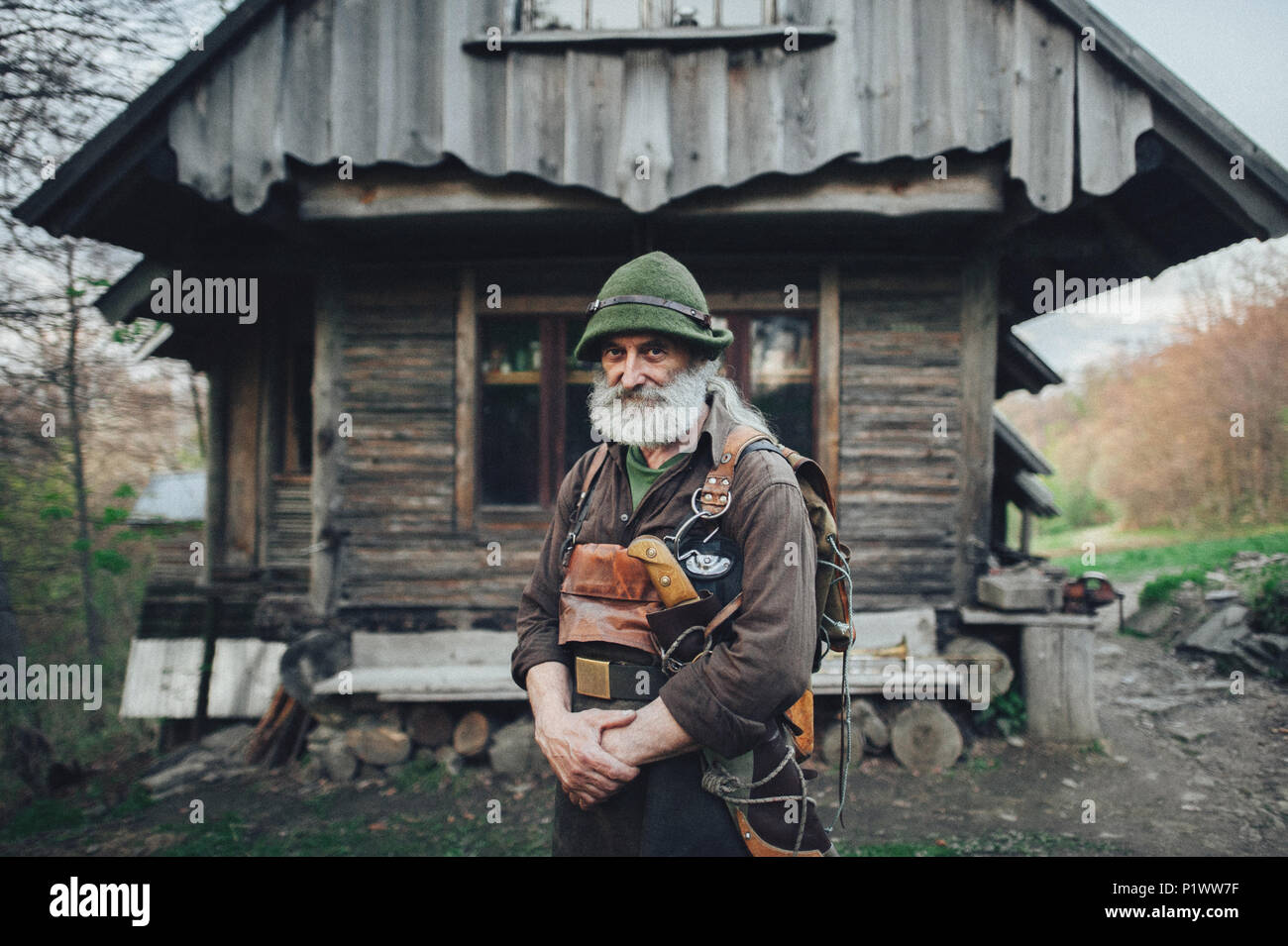 Old forester barbu posant devant de la vieille cabane en bois Banque D'Images