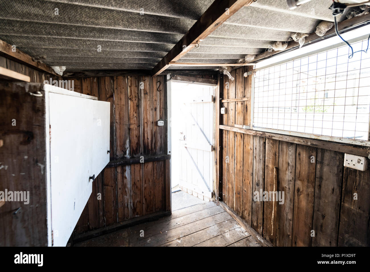 L'intérieur d'un vieux hangar abandonné avec des workbench, placards, étagères, toit de l'amiante et le dangereux. Banque D'Images