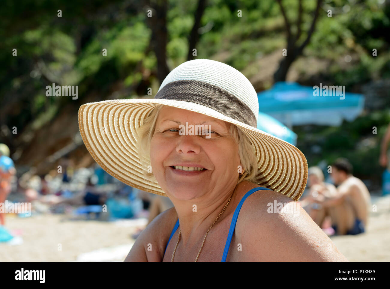 Close-up portrait of smiling woman wearing de chapeau de paille sur la plage. Banque D'Images