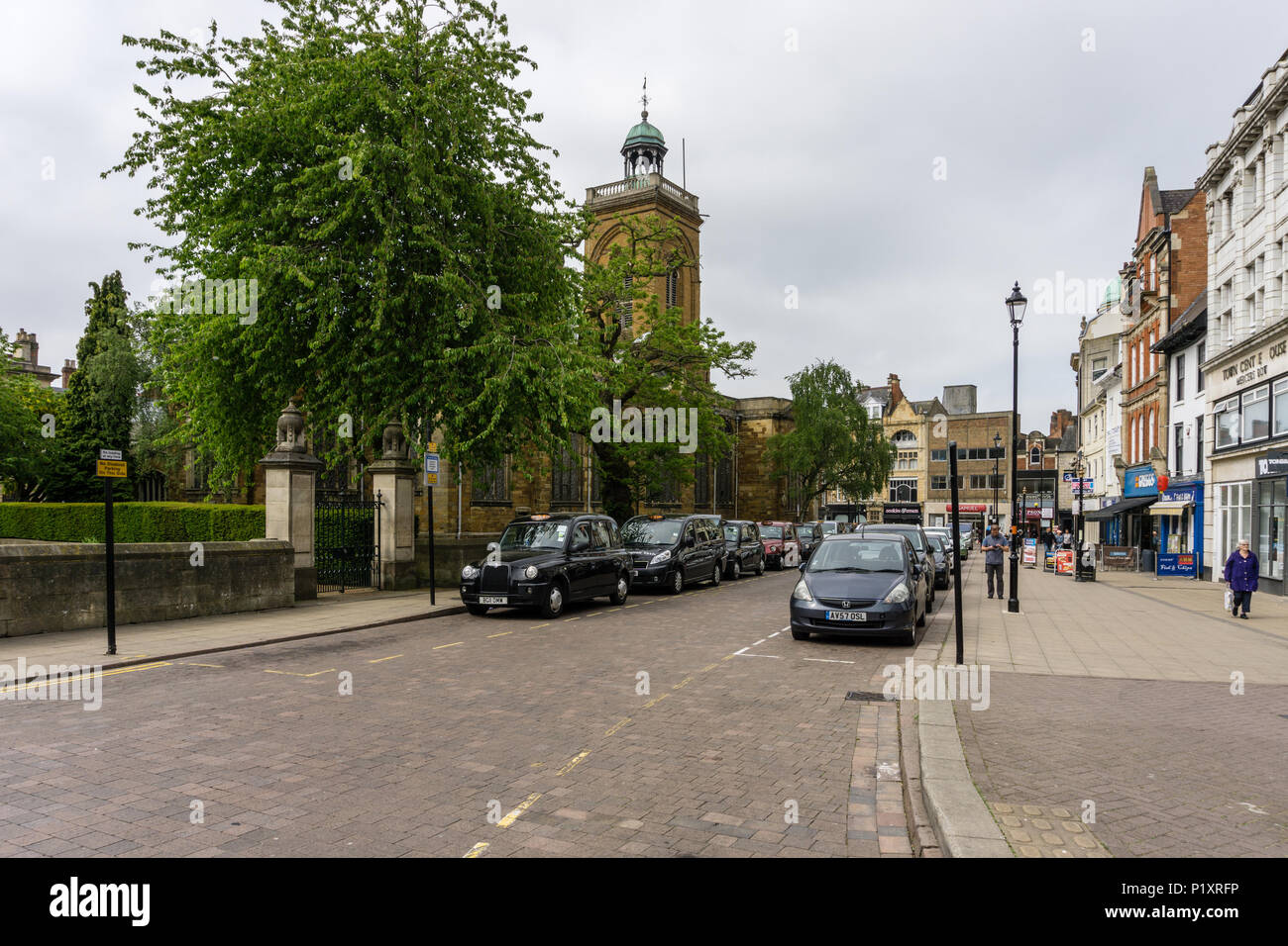 Scène de rue dans le centre-ville de Northampton, Royaume-Uni ; avec un taxi à gauche et la tour de l'église de Saint tous dans l'arrière-plan. Banque D'Images