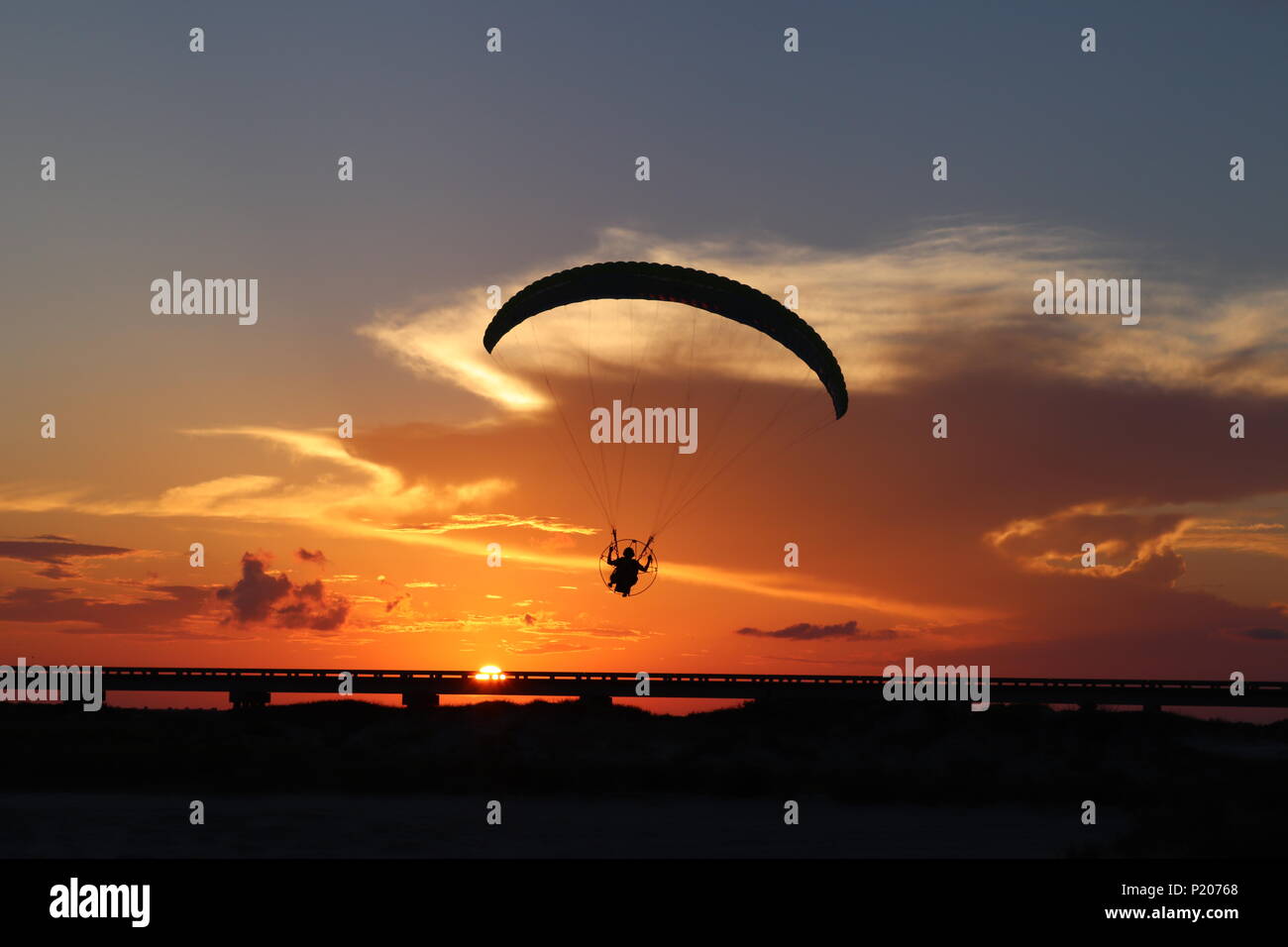 La silhouette d'un parapente, paramoteur, en face d'un ciel orange dans le sud du Texas, aux États-Unis. Le soleil au crépuscule avec un nuage cumulonimbus. Banque D'Images