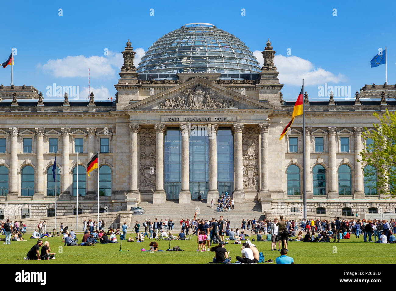 BERLIN, ALLEMAGNE - 28 avril, 2018 : Les gens de vous détendre sur l'herbe, devant le Reichstag, siège du Parlement allemand (Deutscher Bundestag). Banque D'Images
